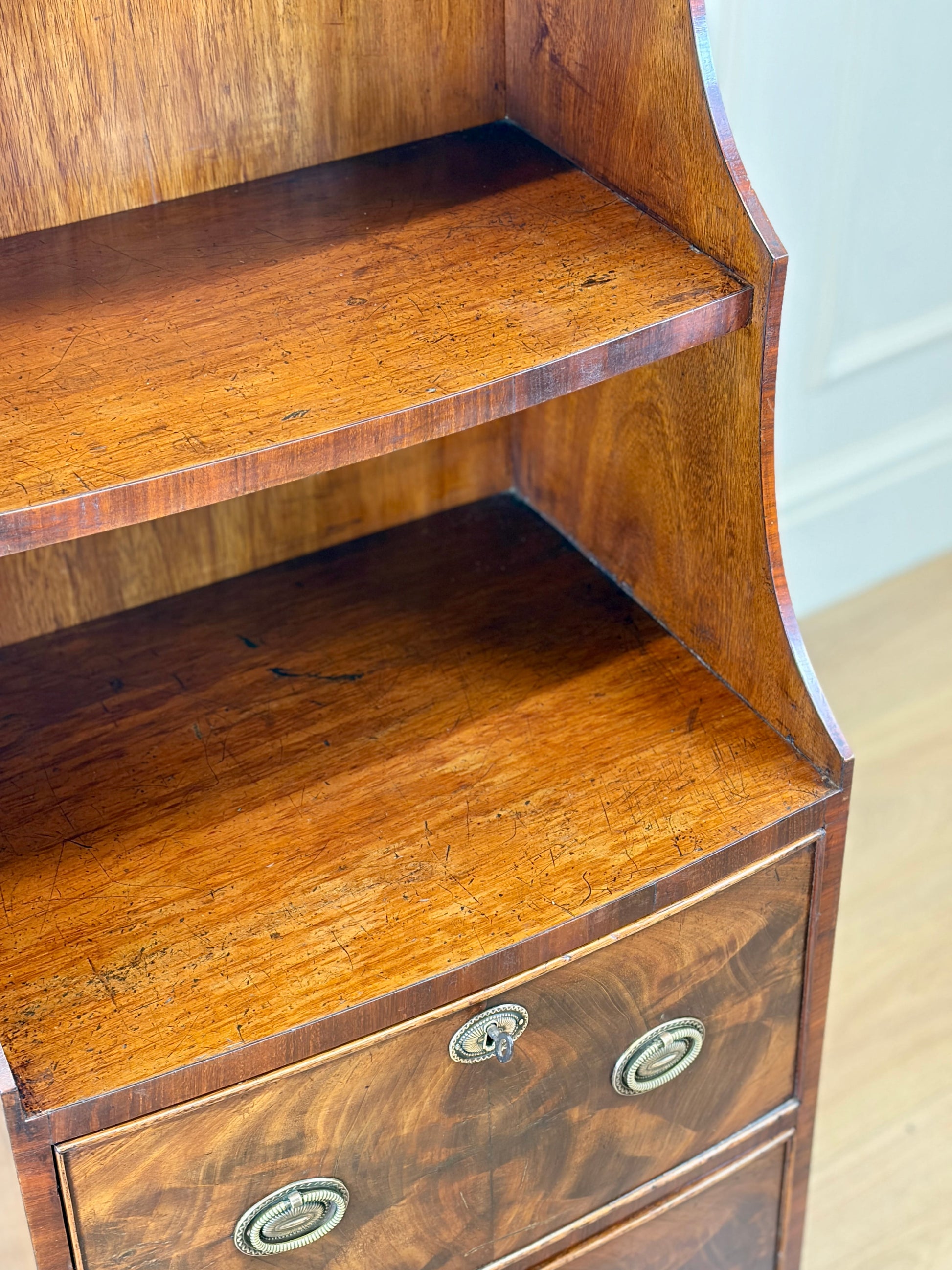 Front view of an antique Georgian mahogany small waterfall bookcase with two deep drawers