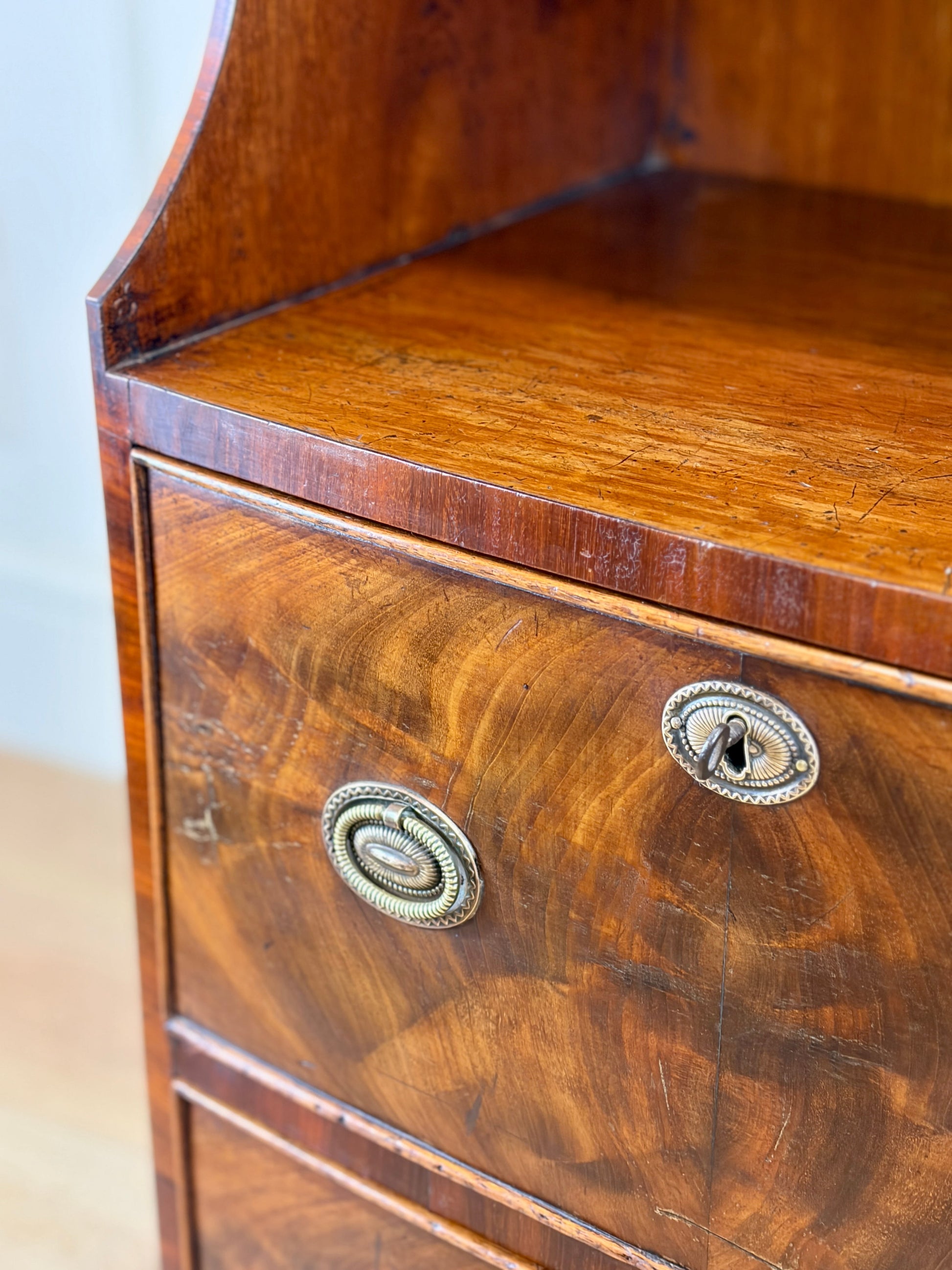 Front view of an antique Georgian mahogany small waterfall bookcase with two deep drawers