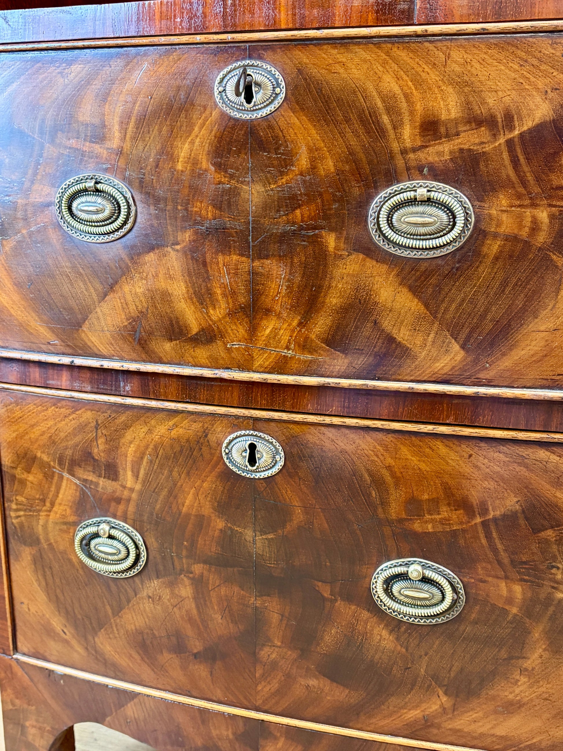 Front view of an antique Georgian mahogany small waterfall bookcase with two deep drawers