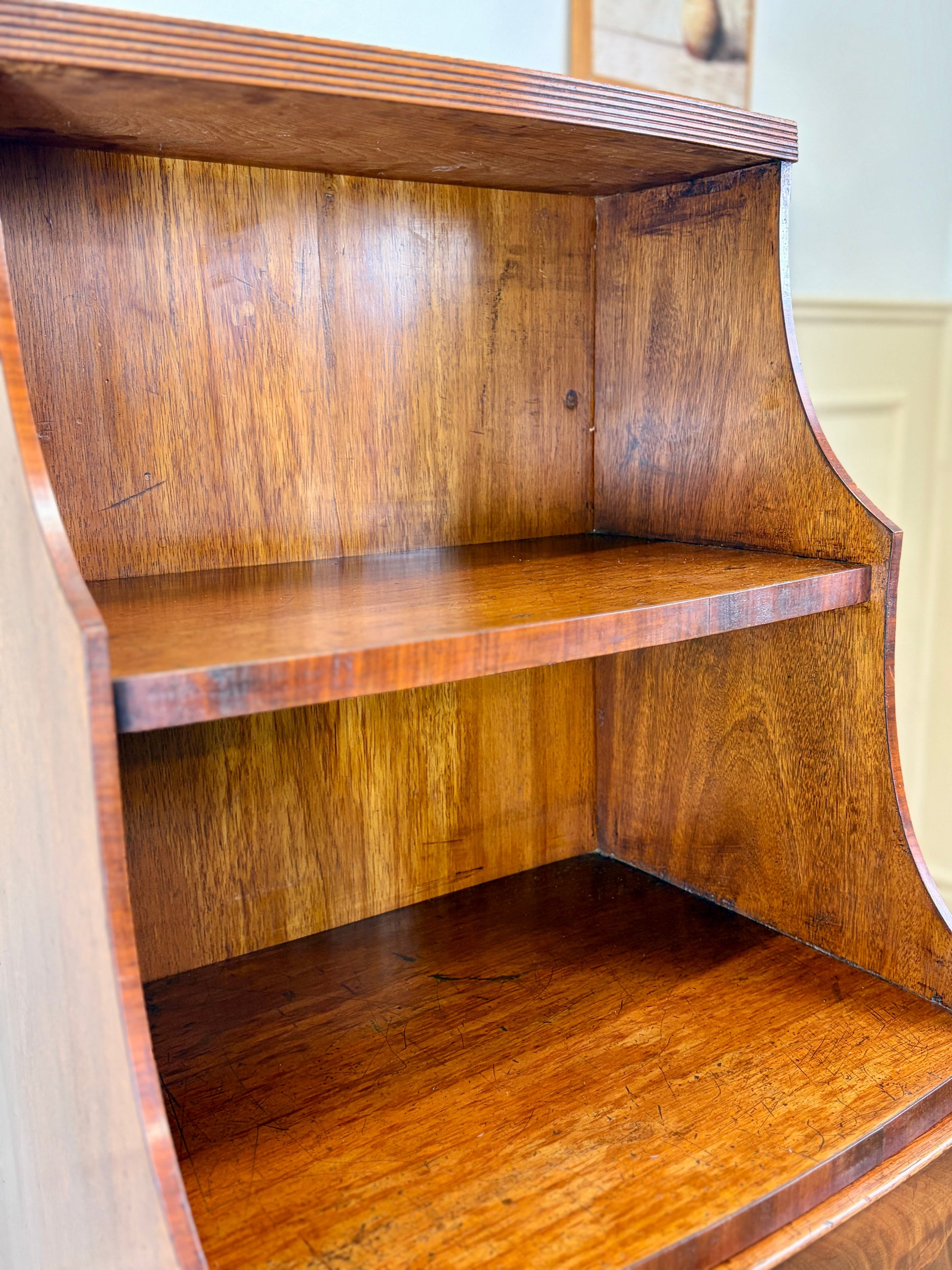 Front view of an antique Georgian mahogany small waterfall bookcase with two deep drawers