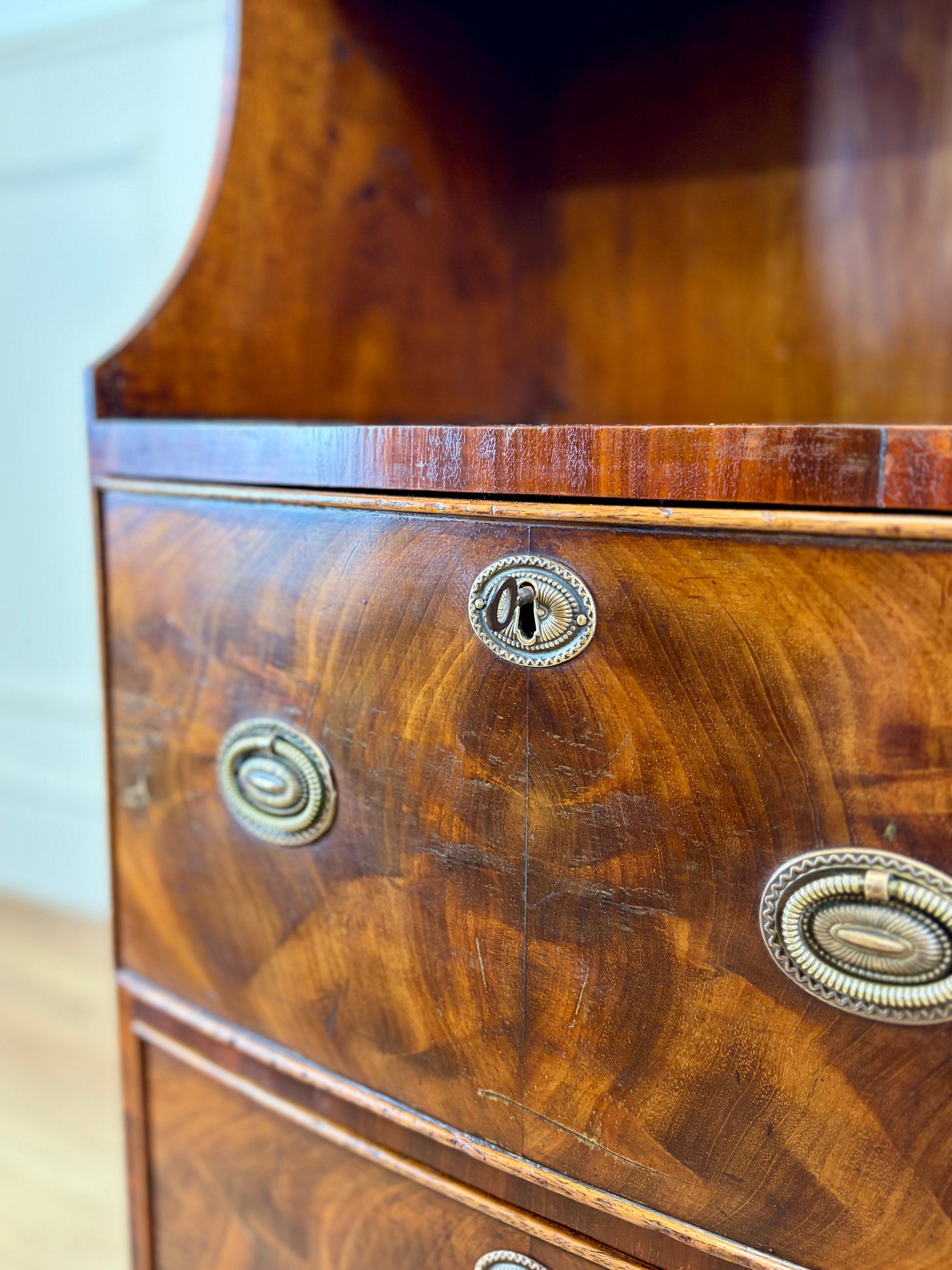 Front view of an antique Georgian mahogany small waterfall bookcase with two deep drawers