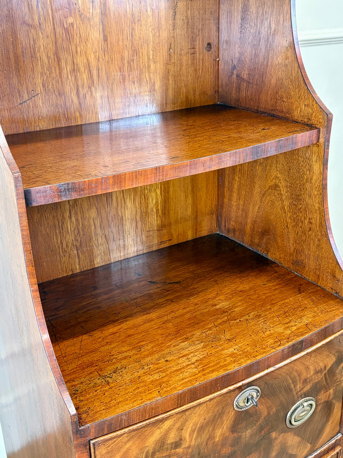 Front view of an antique Georgian mahogany small waterfall bookcase with two deep drawers
