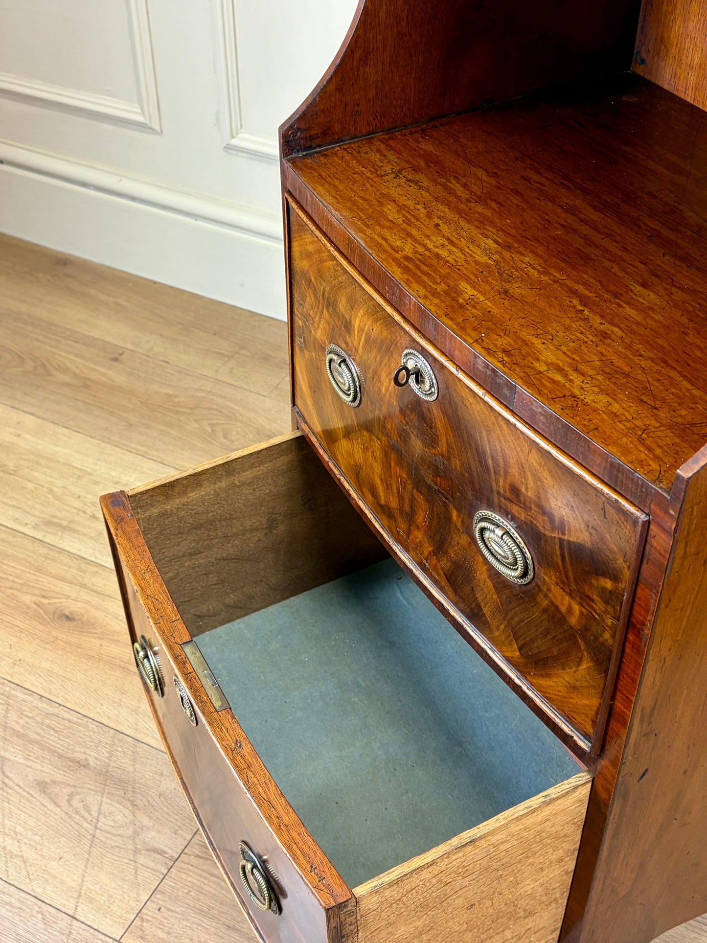 Front view of an antique Georgian mahogany small waterfall bookcase with two deep drawers