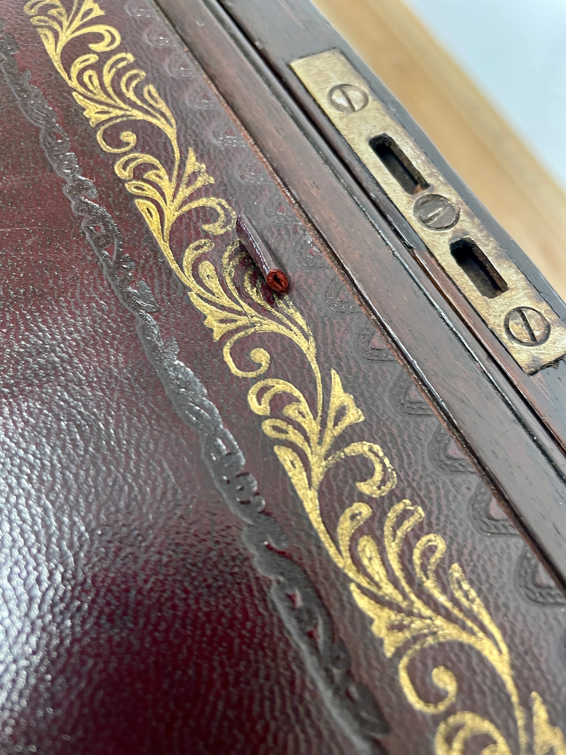 Close-up of a leather-bound book with gold embossed design and brass hardware.