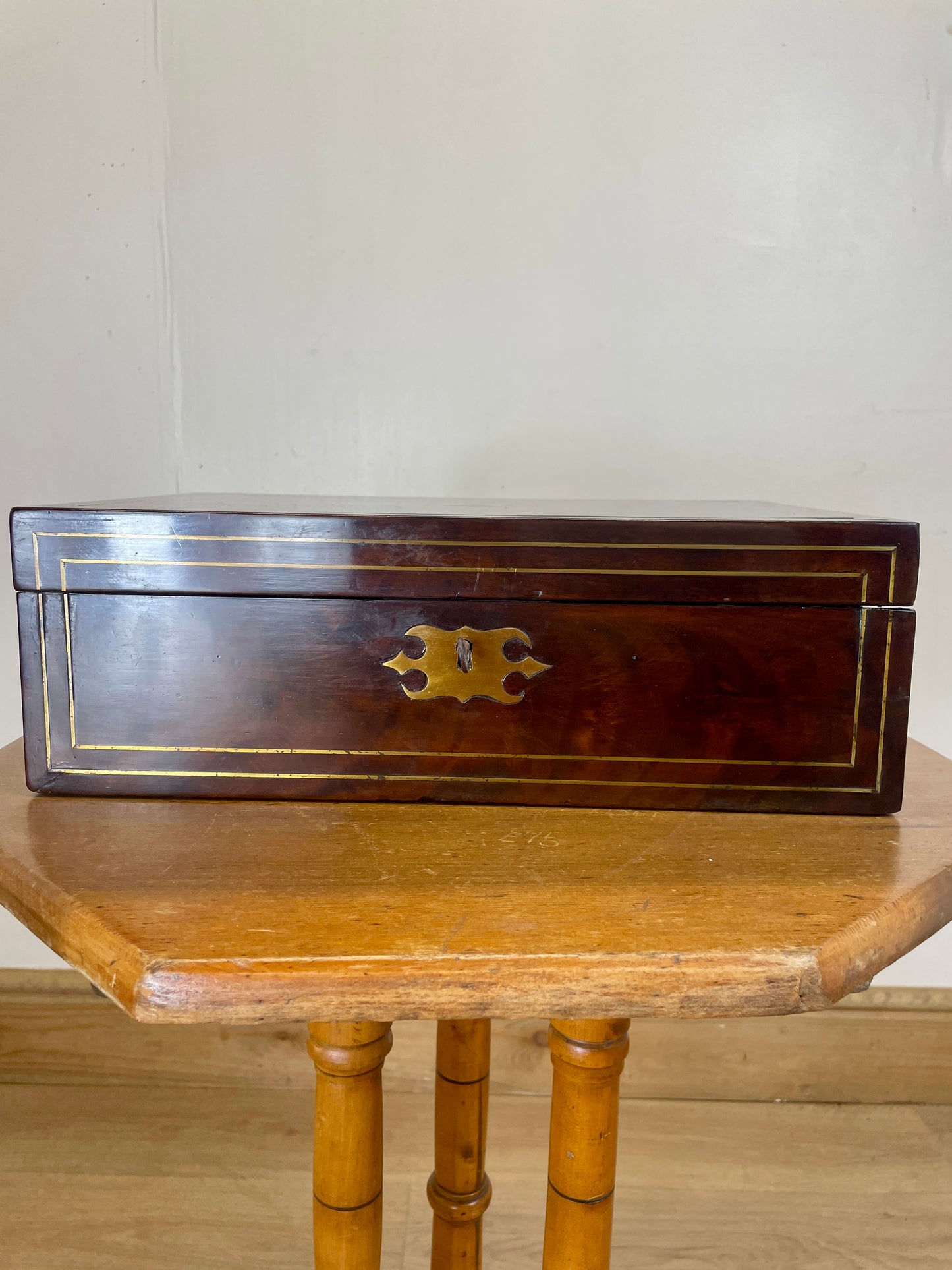 Wooden box with brass handle on a wooden table against a white wall