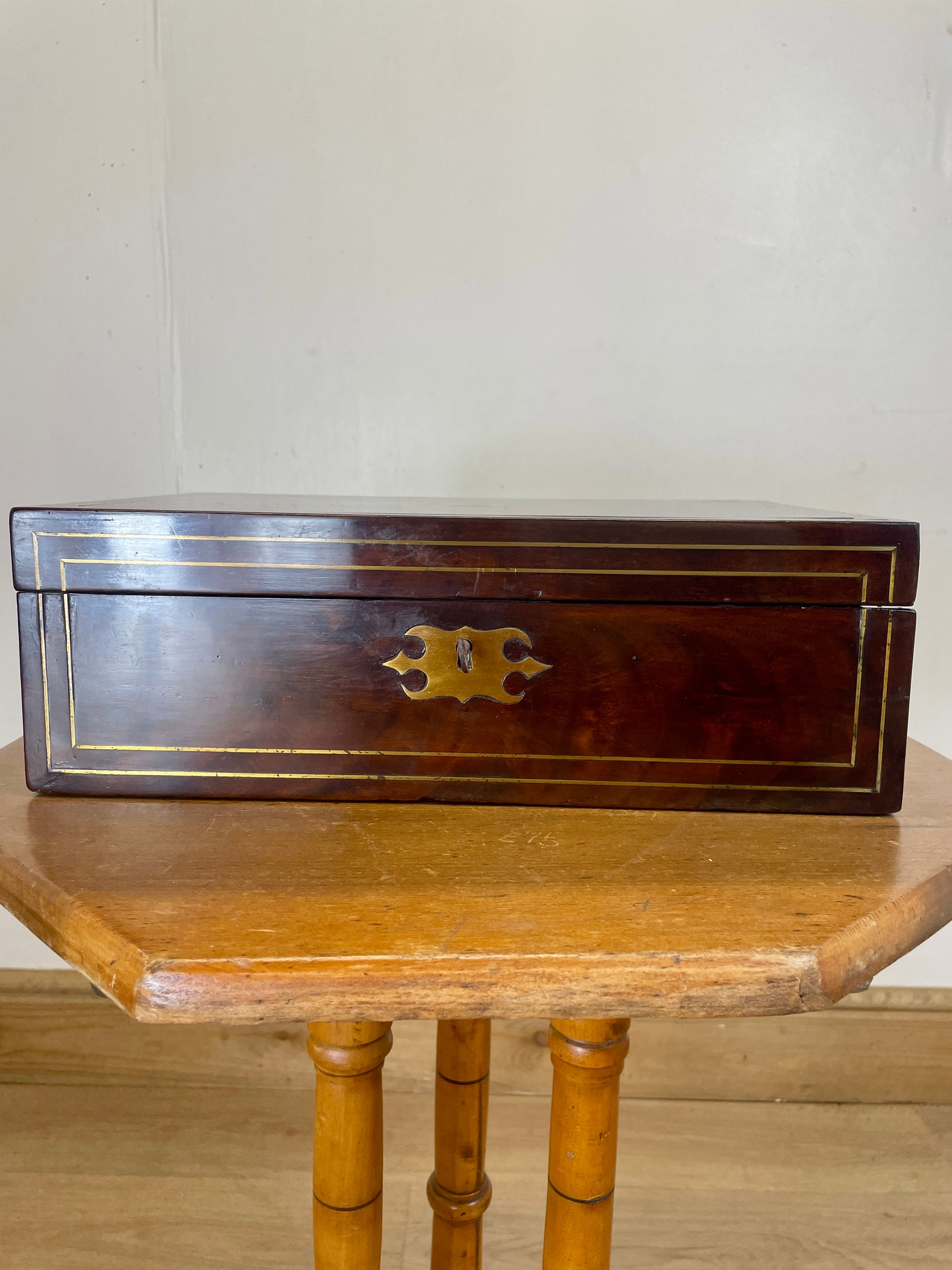 Wooden box with brass handle on a wooden table against a white wall