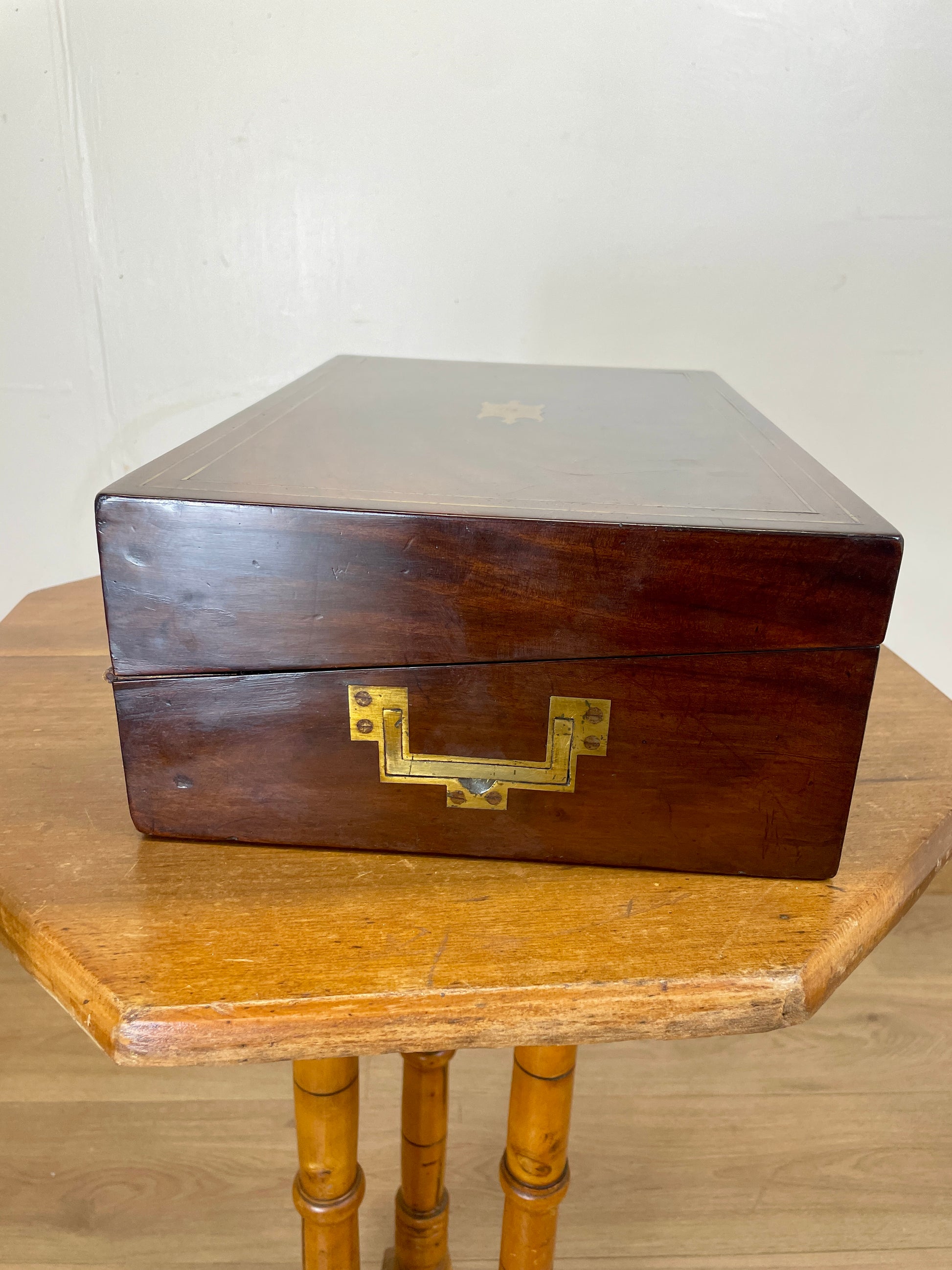 Wooden box with brass lock on a wooden table against a white wall