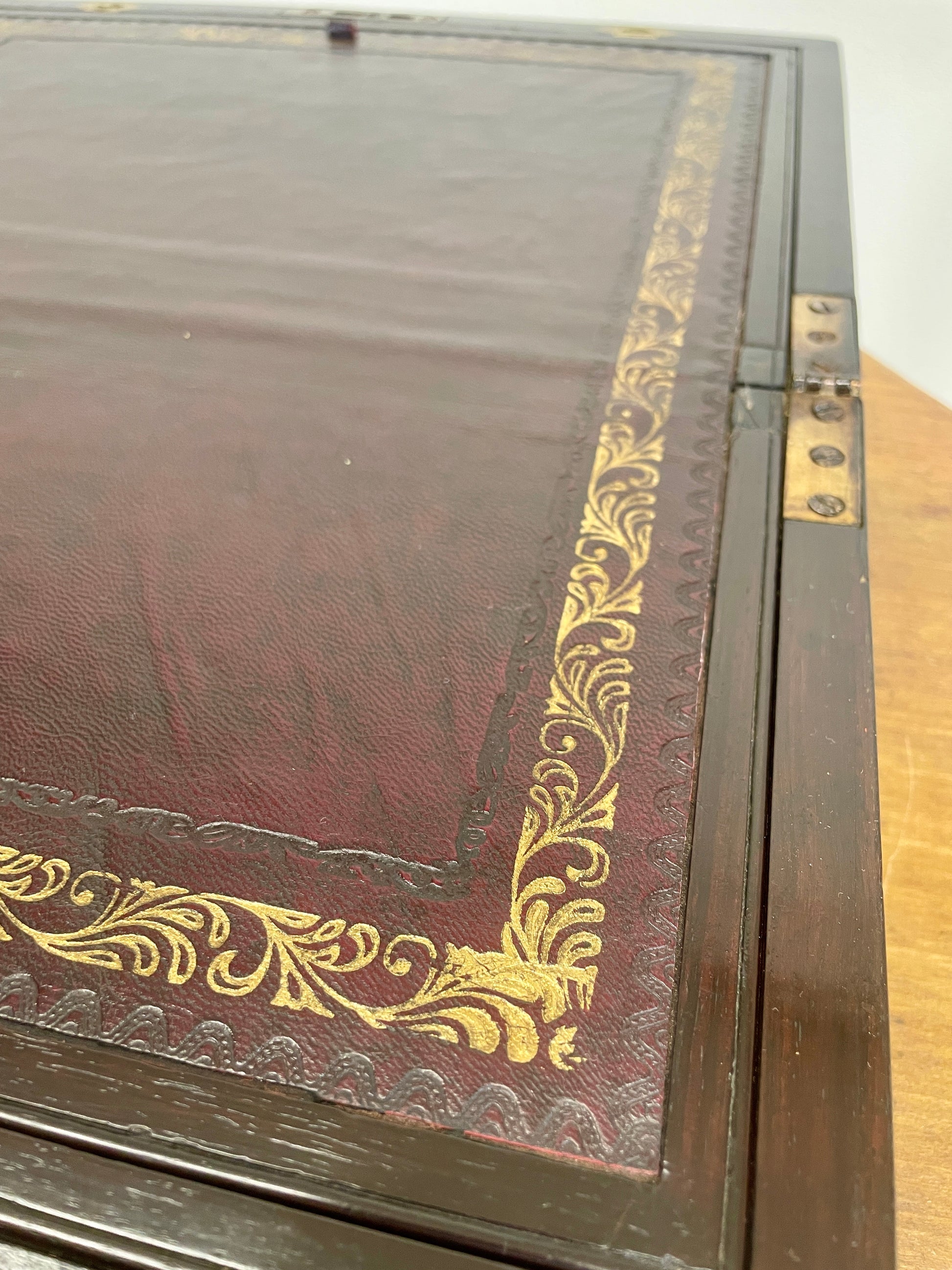 Decorative wooden box with gold embossed patterns on a wooden surface.