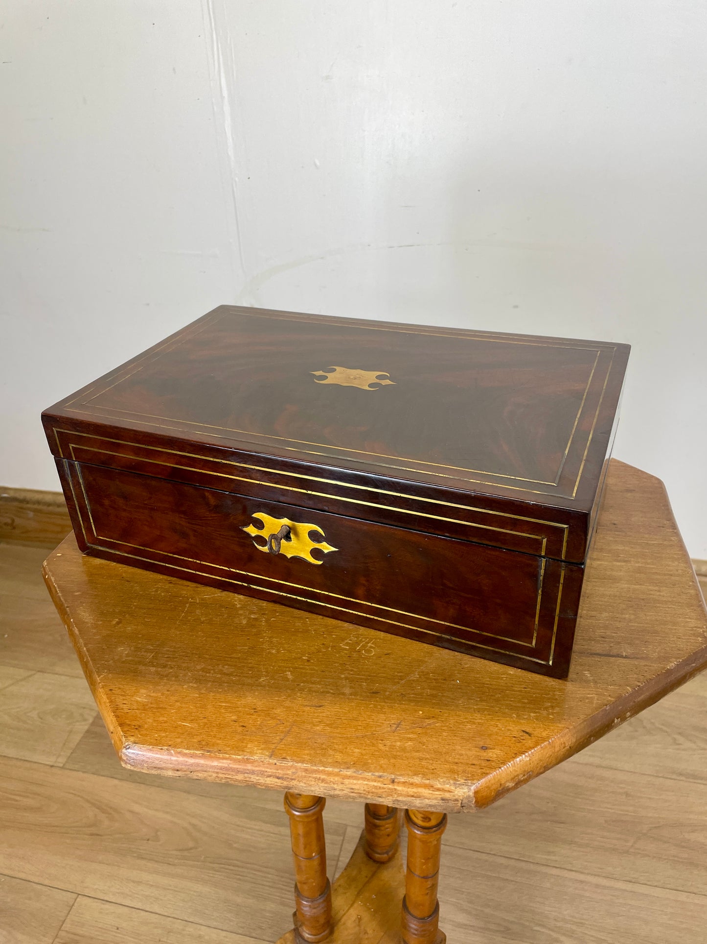 Wooden jewelry box with a gold emblem on a wooden table against a white wall