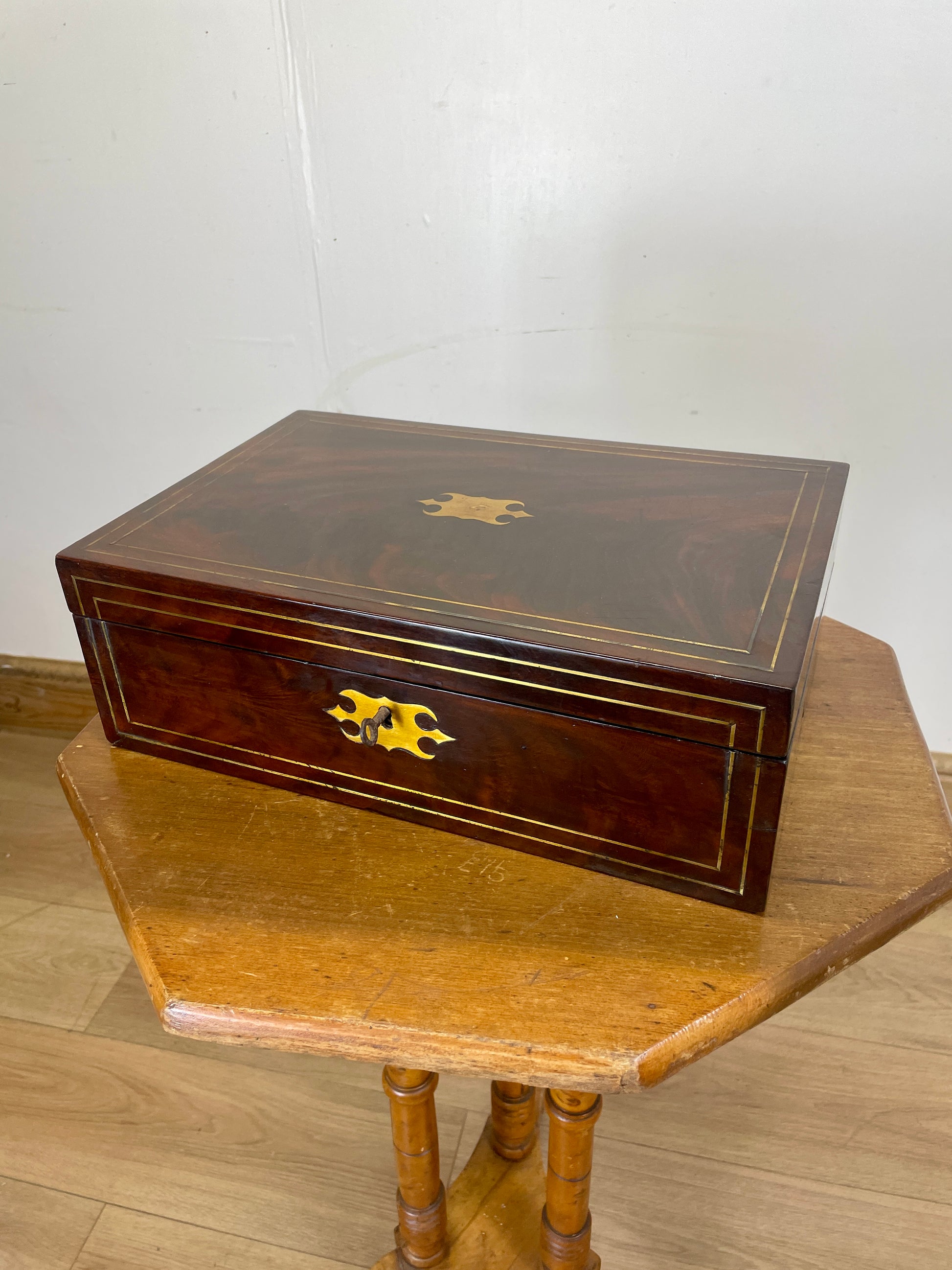 Wooden jewelry box with a gold emblem on a wooden table against a white wall