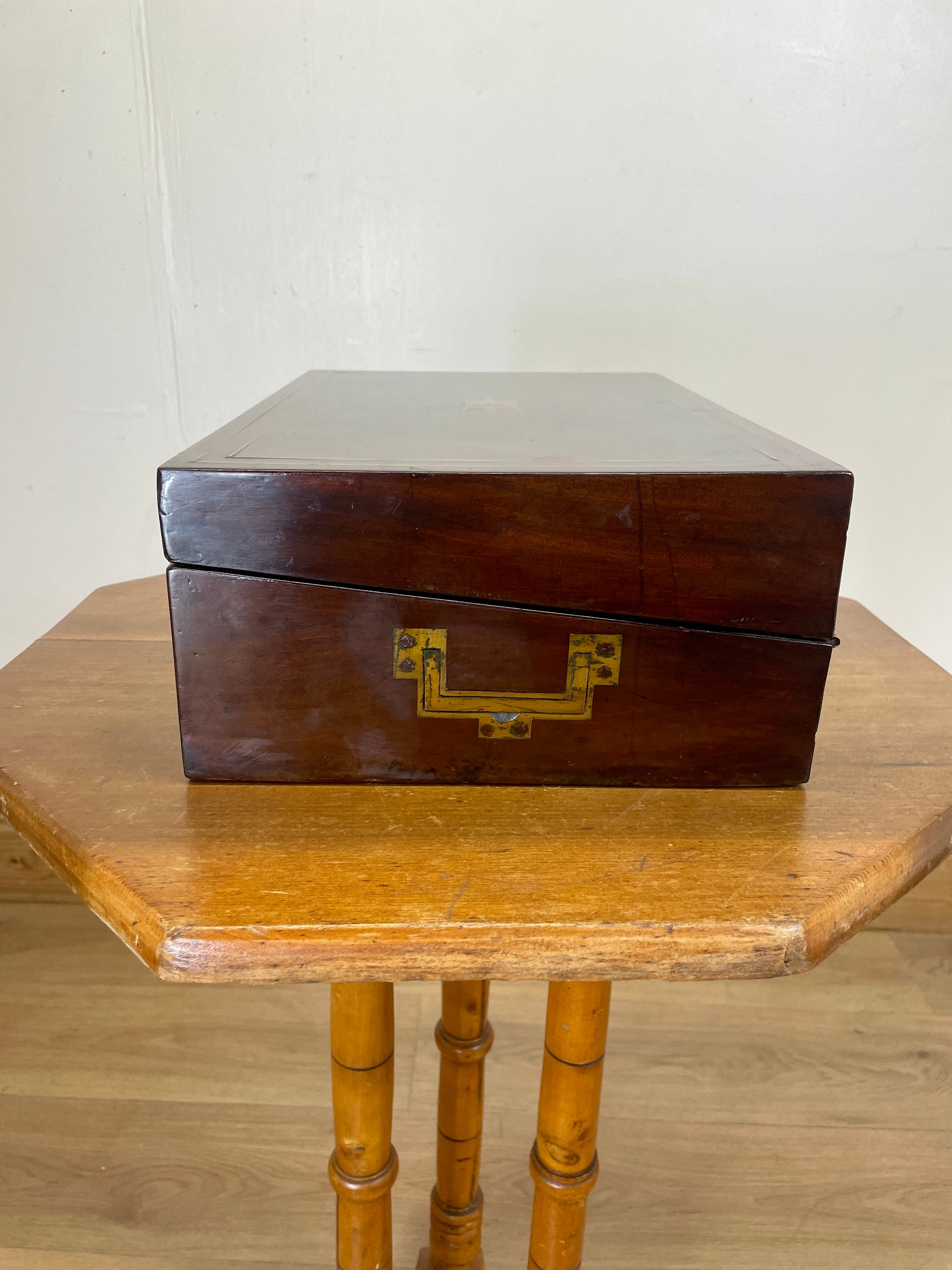 Wooden box with a gold handle on a wooden table against a white wall