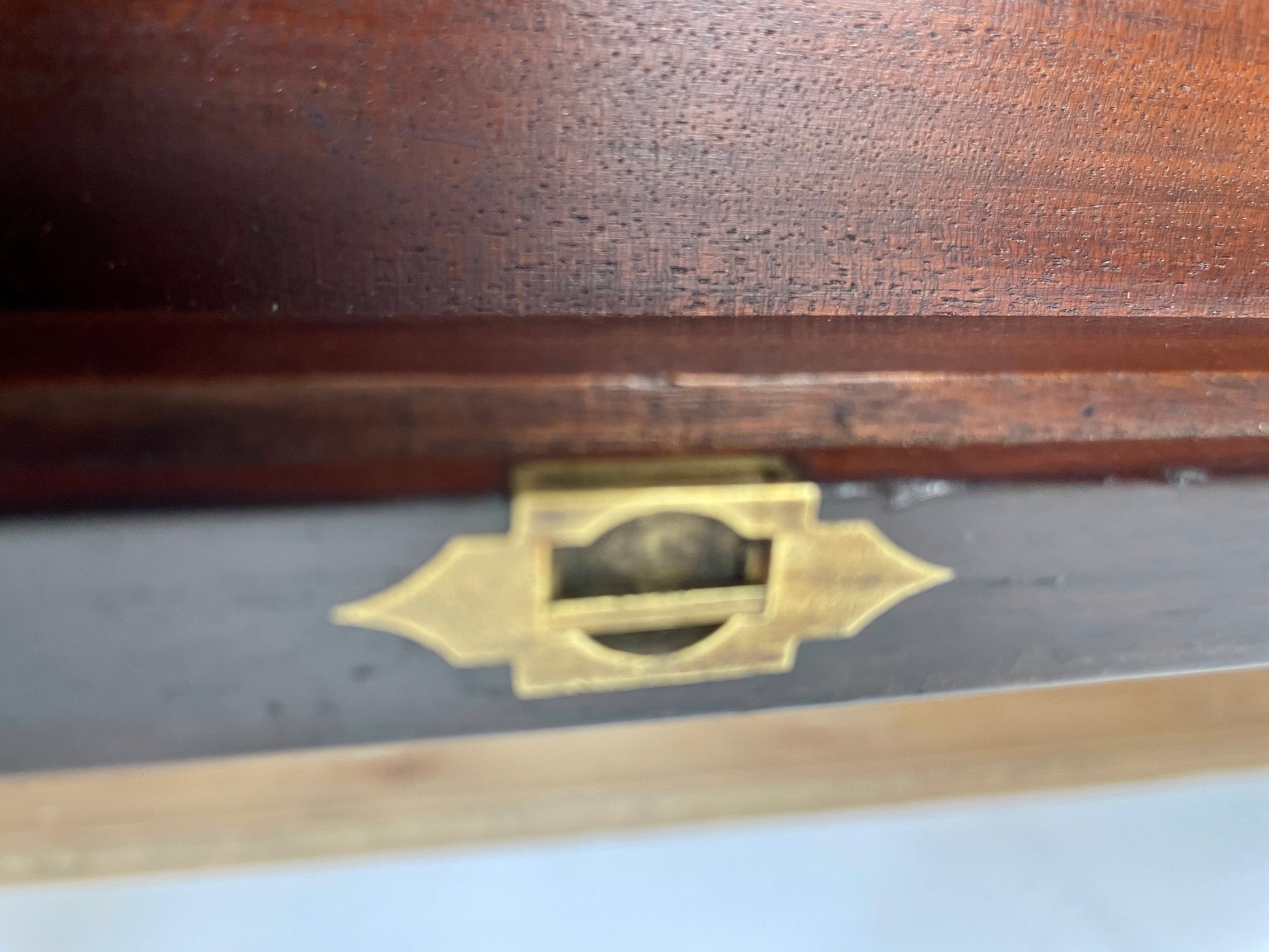 Wooden box with brass lock and decorative emblem on a light background
