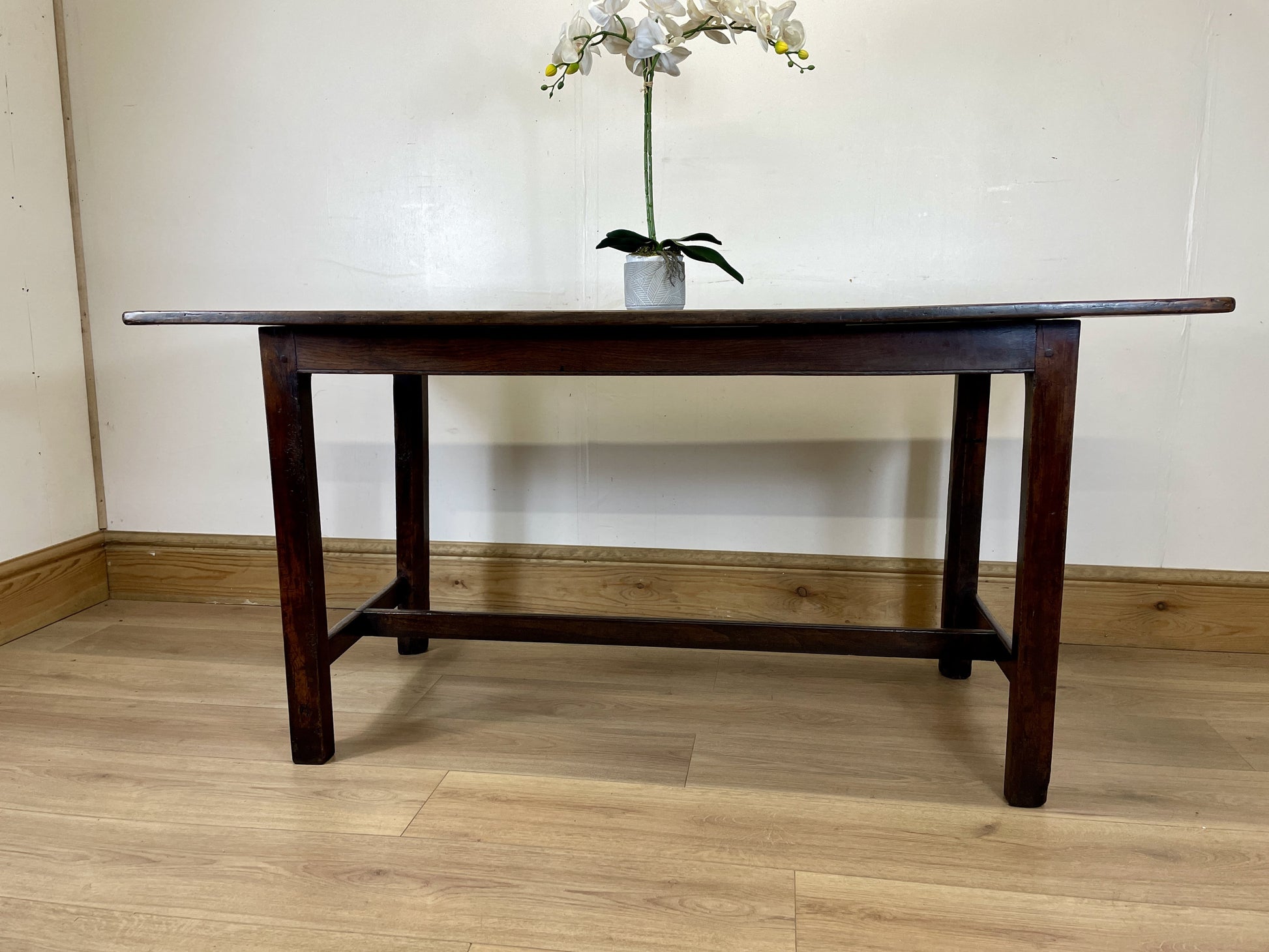 Wooden table with a vase of flowers on a wooden floor.