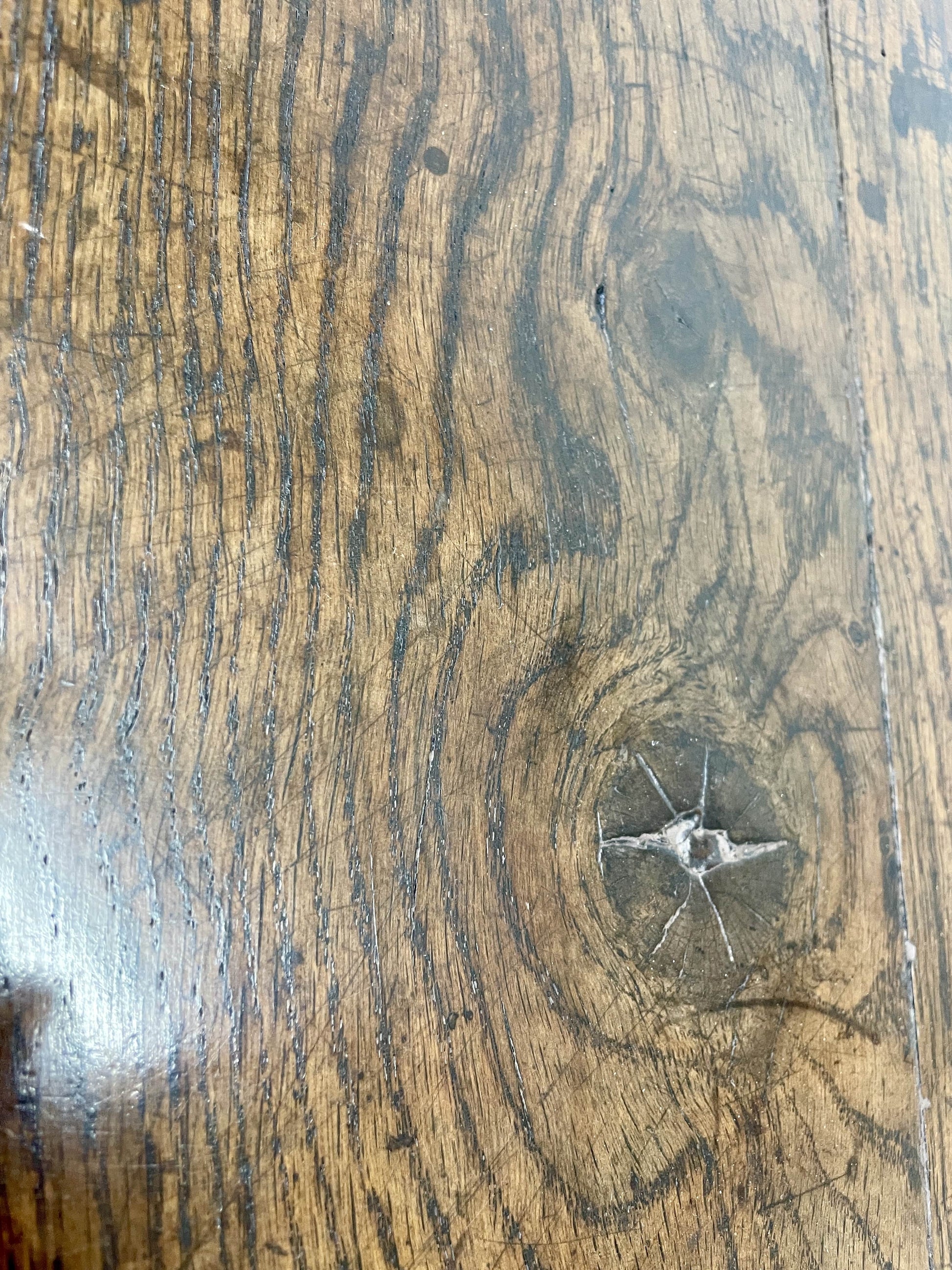 Close-up of a wooden surface with visible grain and a small scratch.
