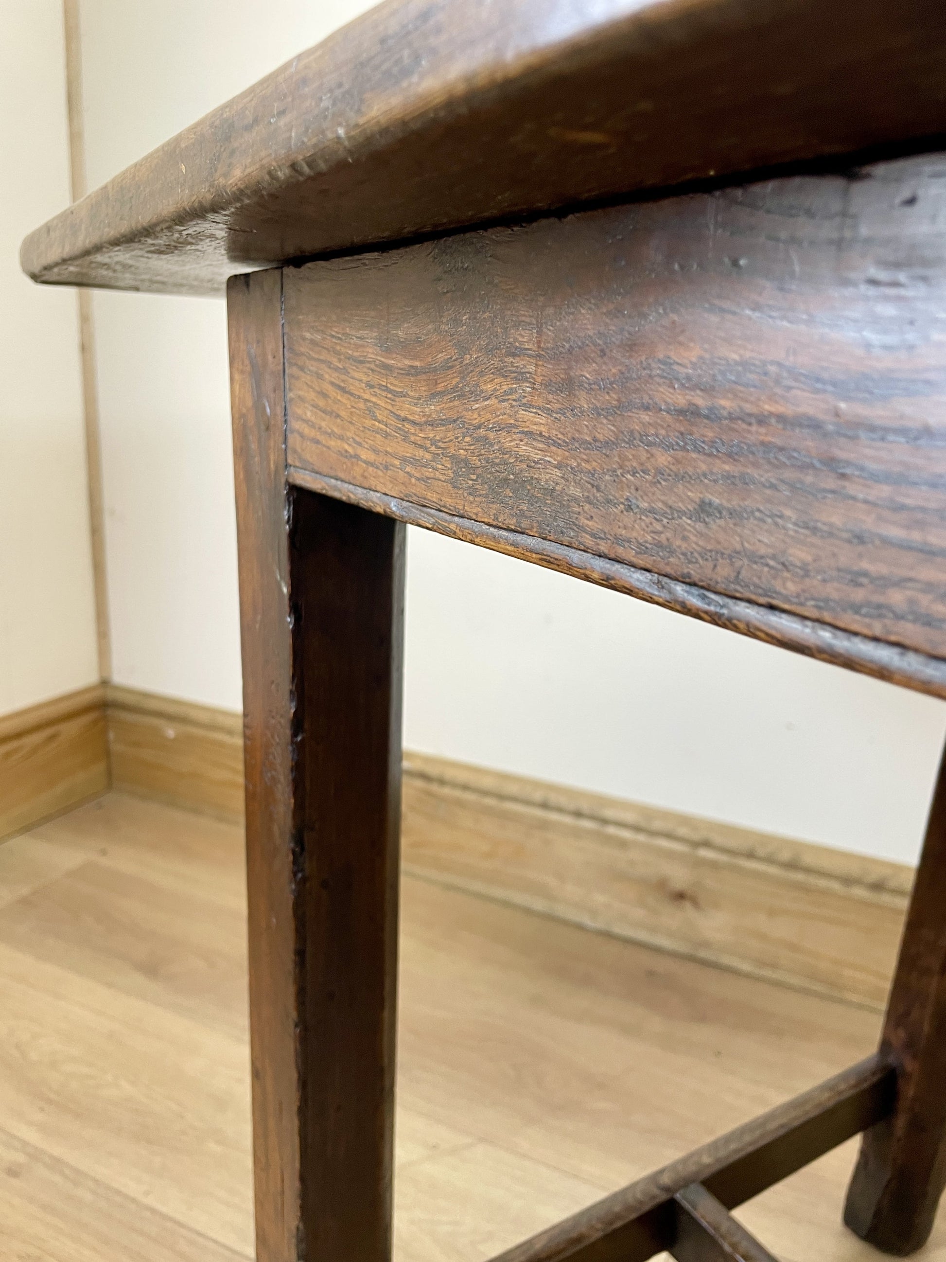 Close-up of a wooden table with a worn surface on a wooden floor.