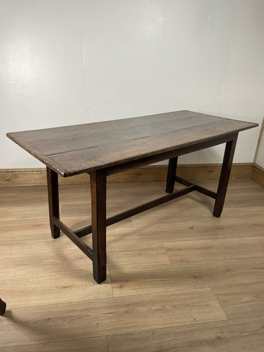 Wooden table with a rustic design on a wooden floor against a white wall.