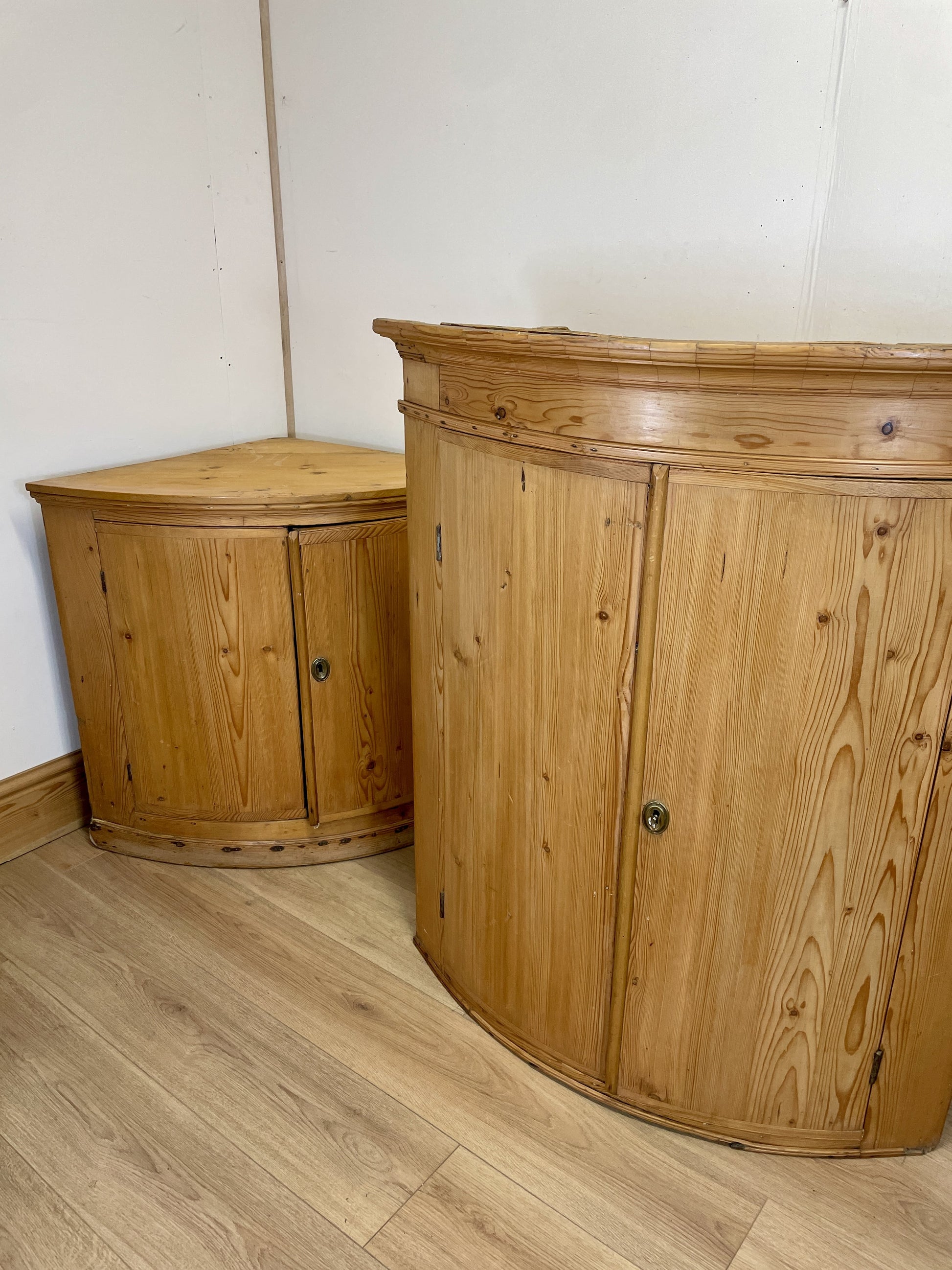 Two wooden cabinets against a white wall on a wooden floor.