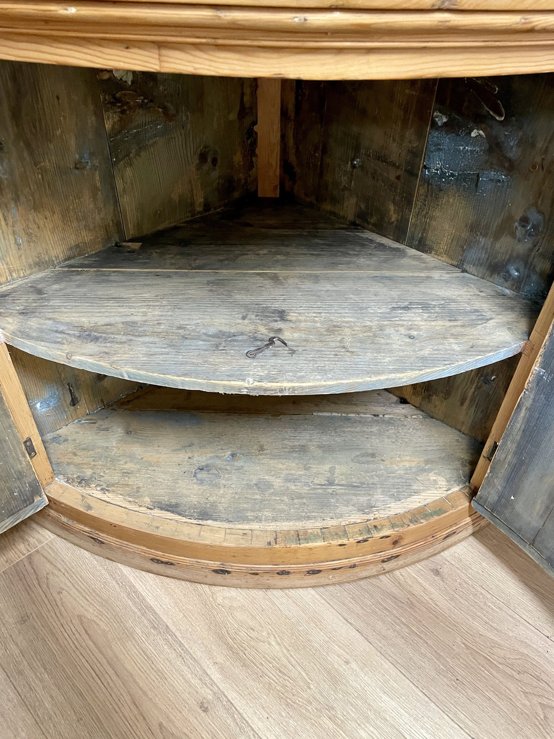 Wooden corner shelf with three tiers in a rustic setting