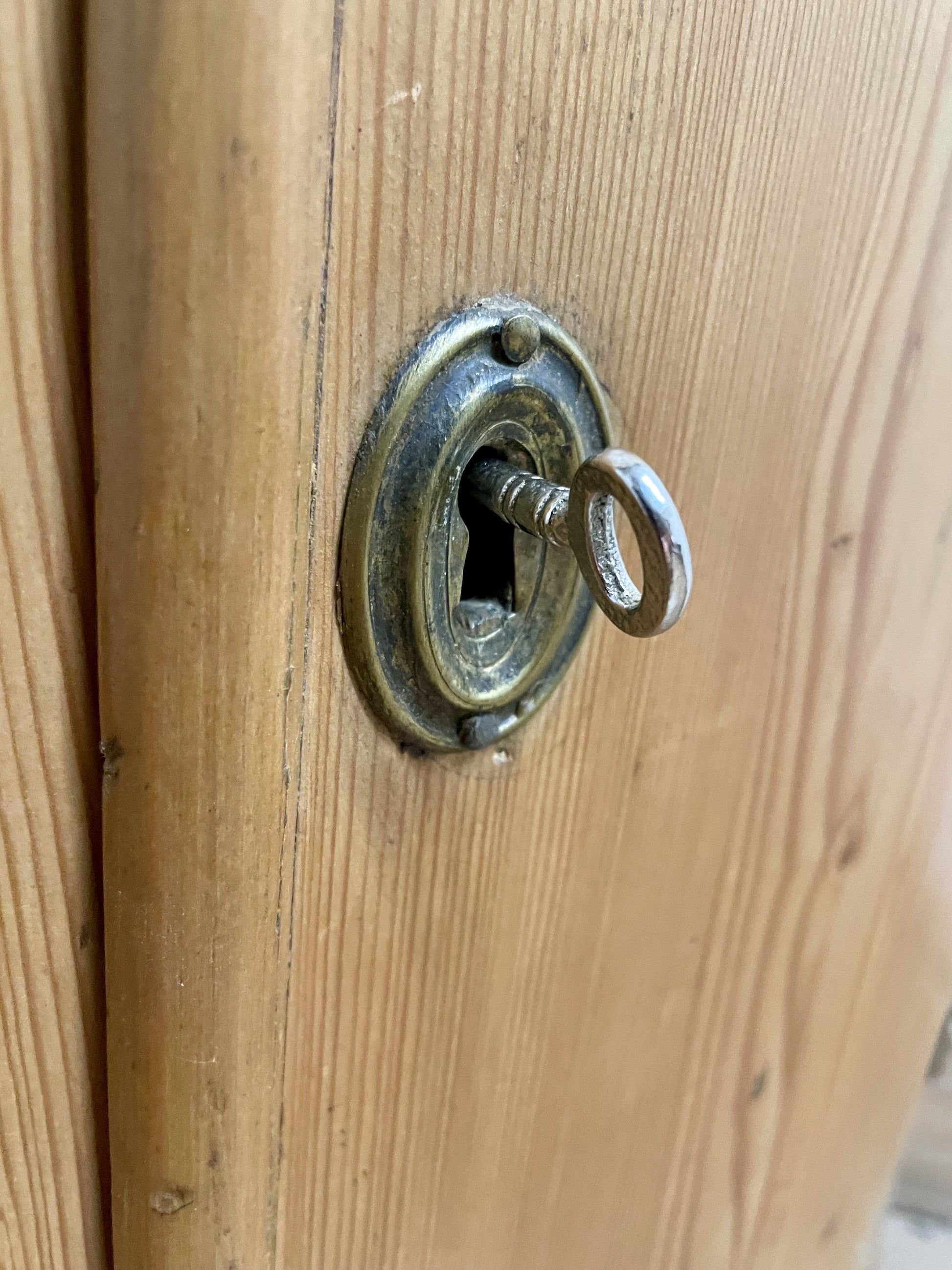 Close-up of a wooden door with a brass lock and keyhole.