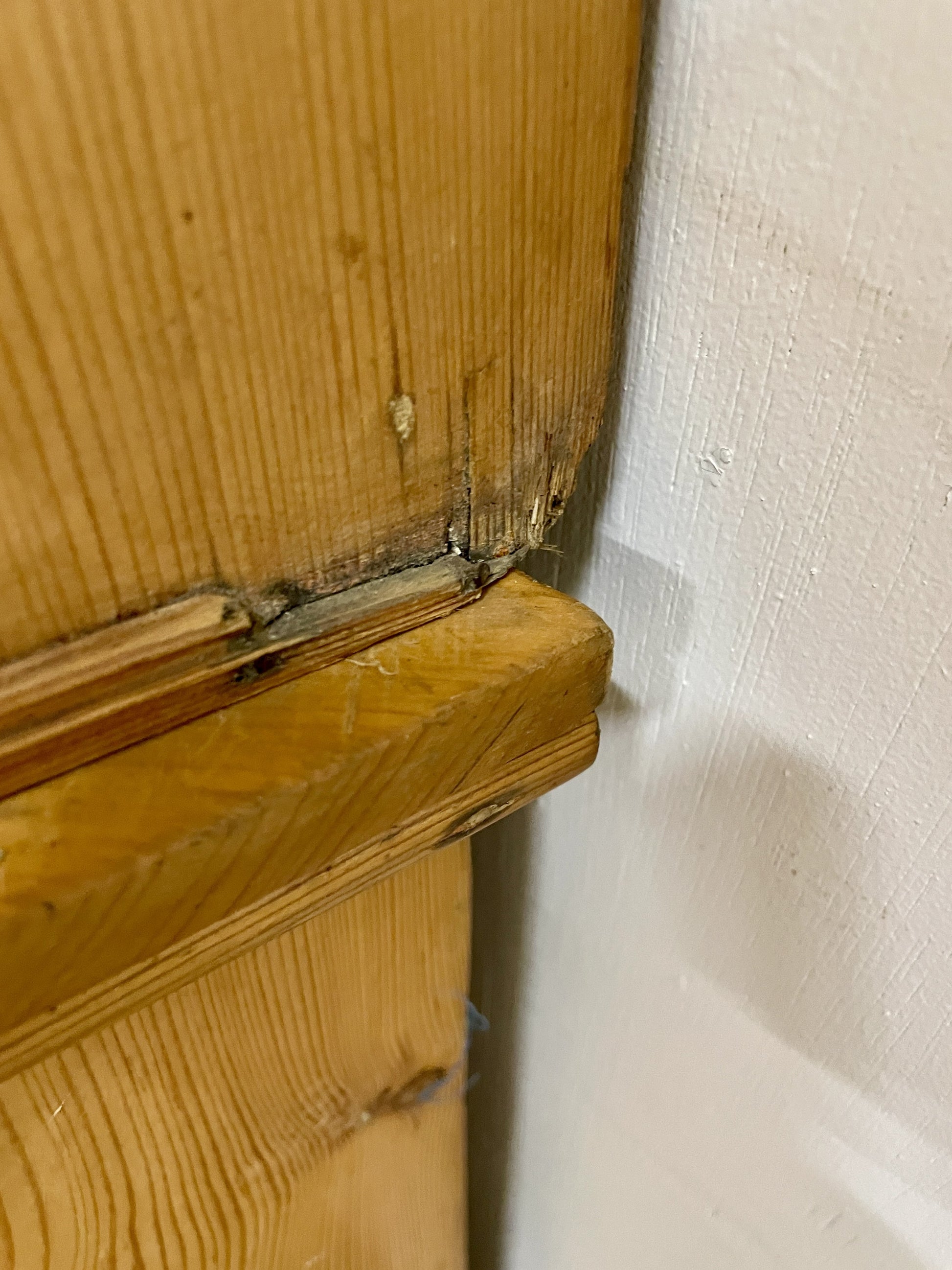 Wooden door with a gap between it and the wall
