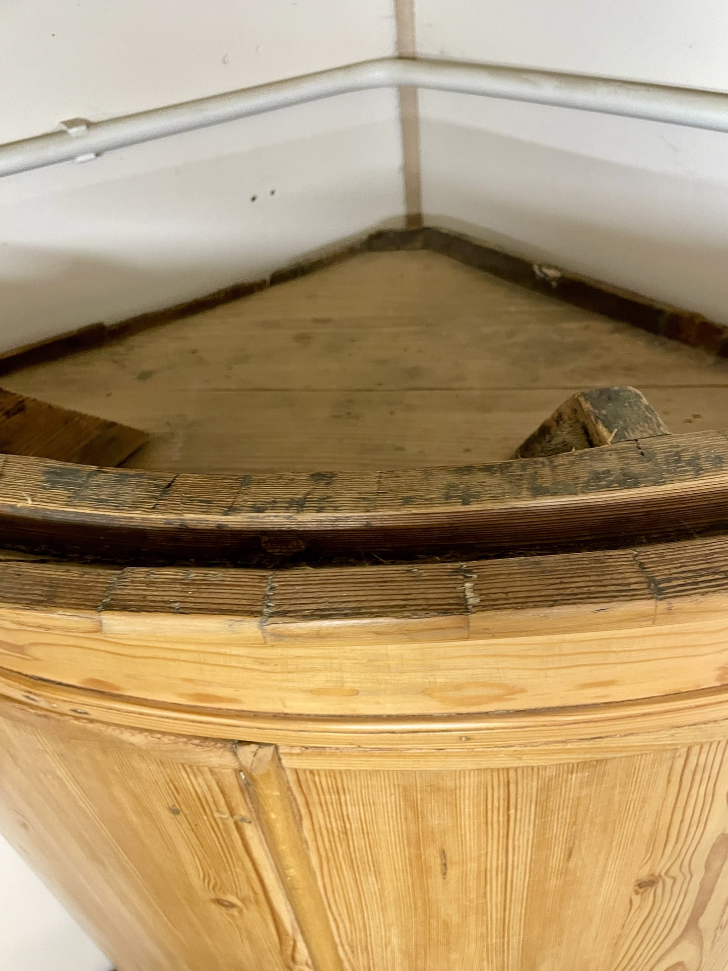 Wooden corner bench with a worn surface in a corner of a room.