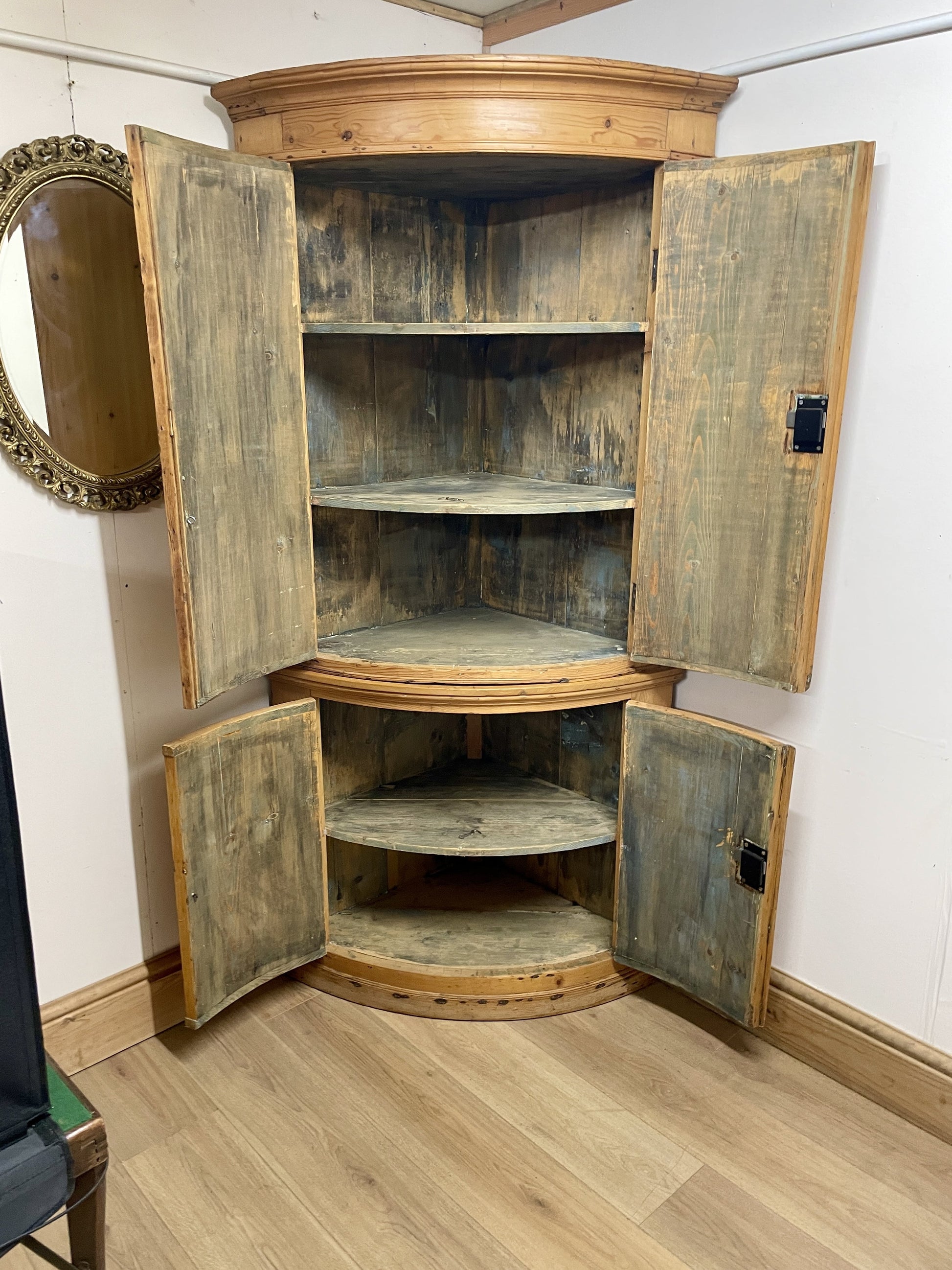 Wooden corner cabinet with open doors in a room setting