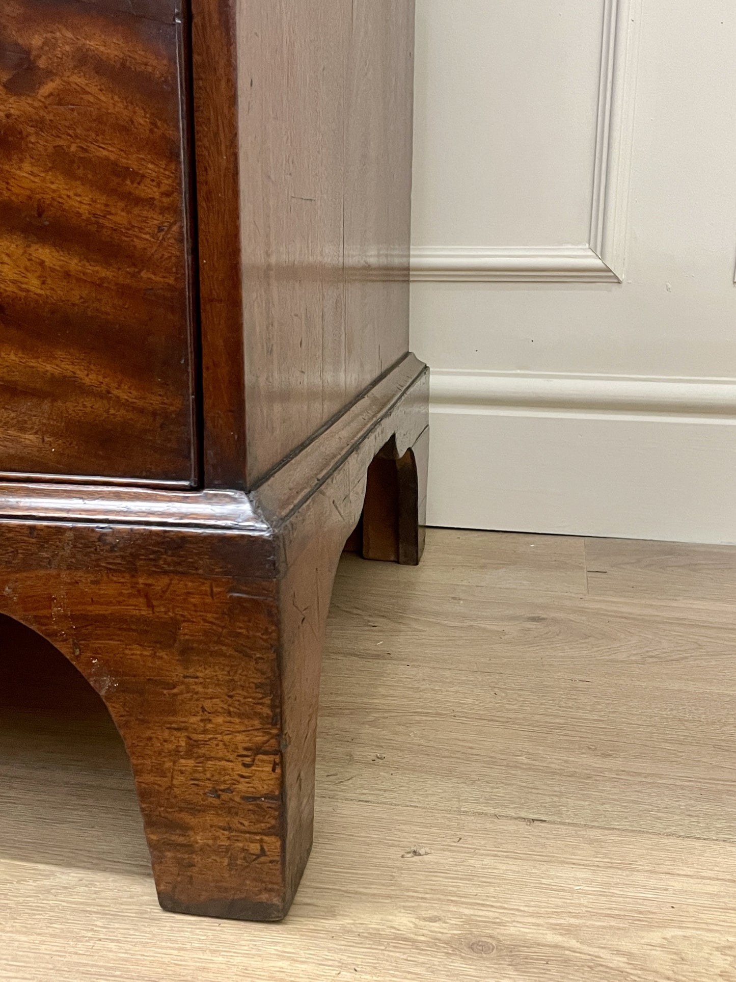 Wooden cabinet corner with a white paneled wall in the background