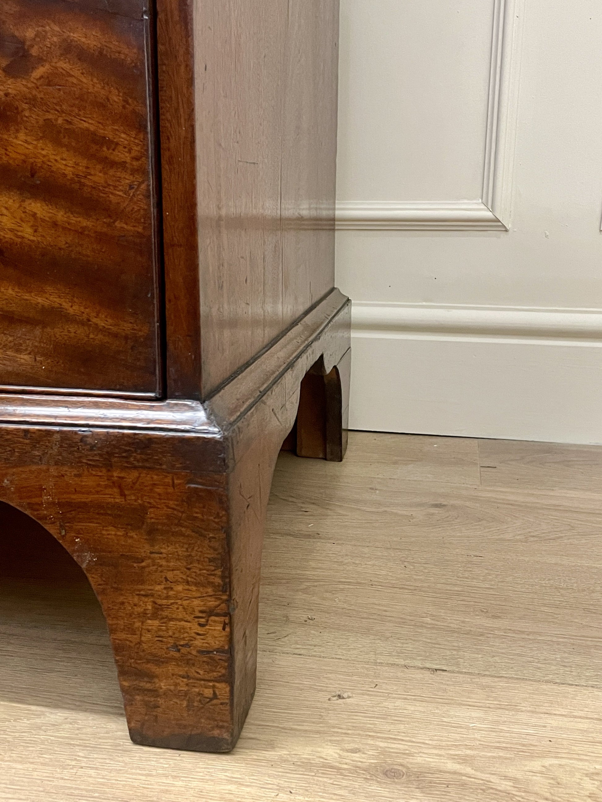 Wooden cabinet corner with a white paneled wall in the background