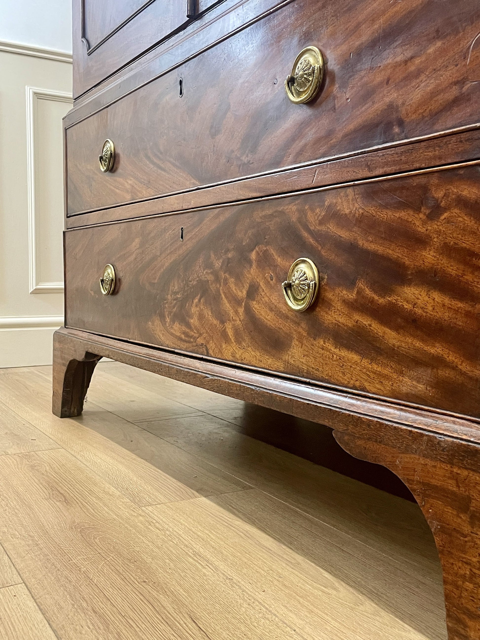 Wooden dresser with brass handles on a wooden floor.