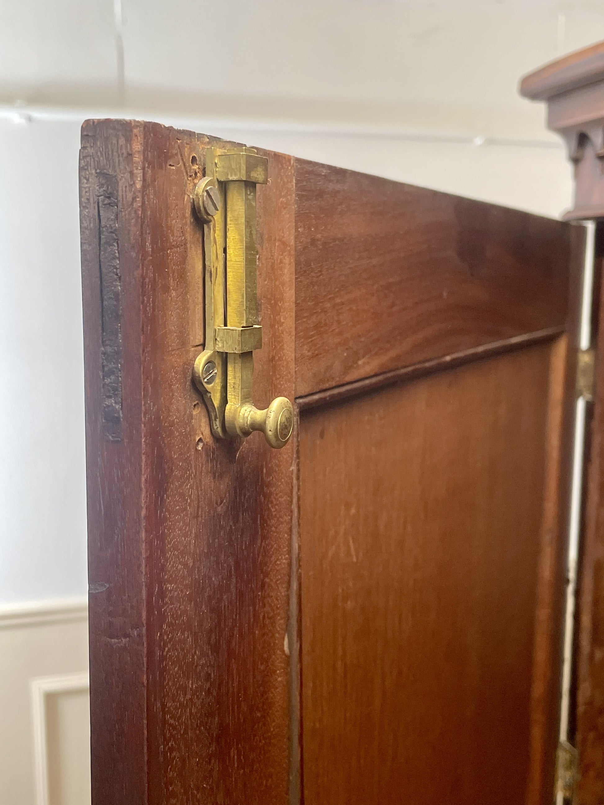 Close-up of a wooden cabinet with brass hinges and handles.