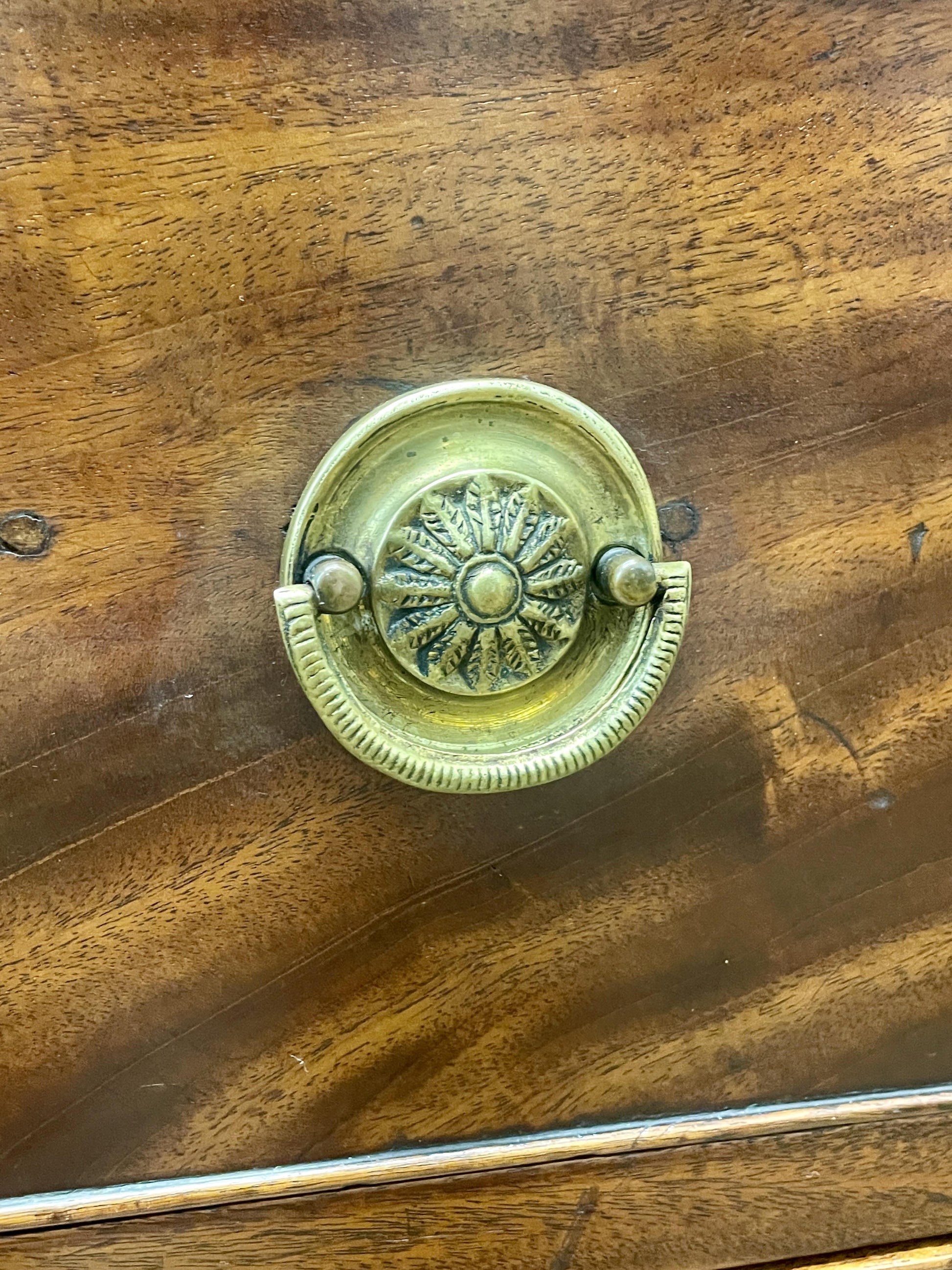 Close-up of a wooden surface with a decorative brass handle.