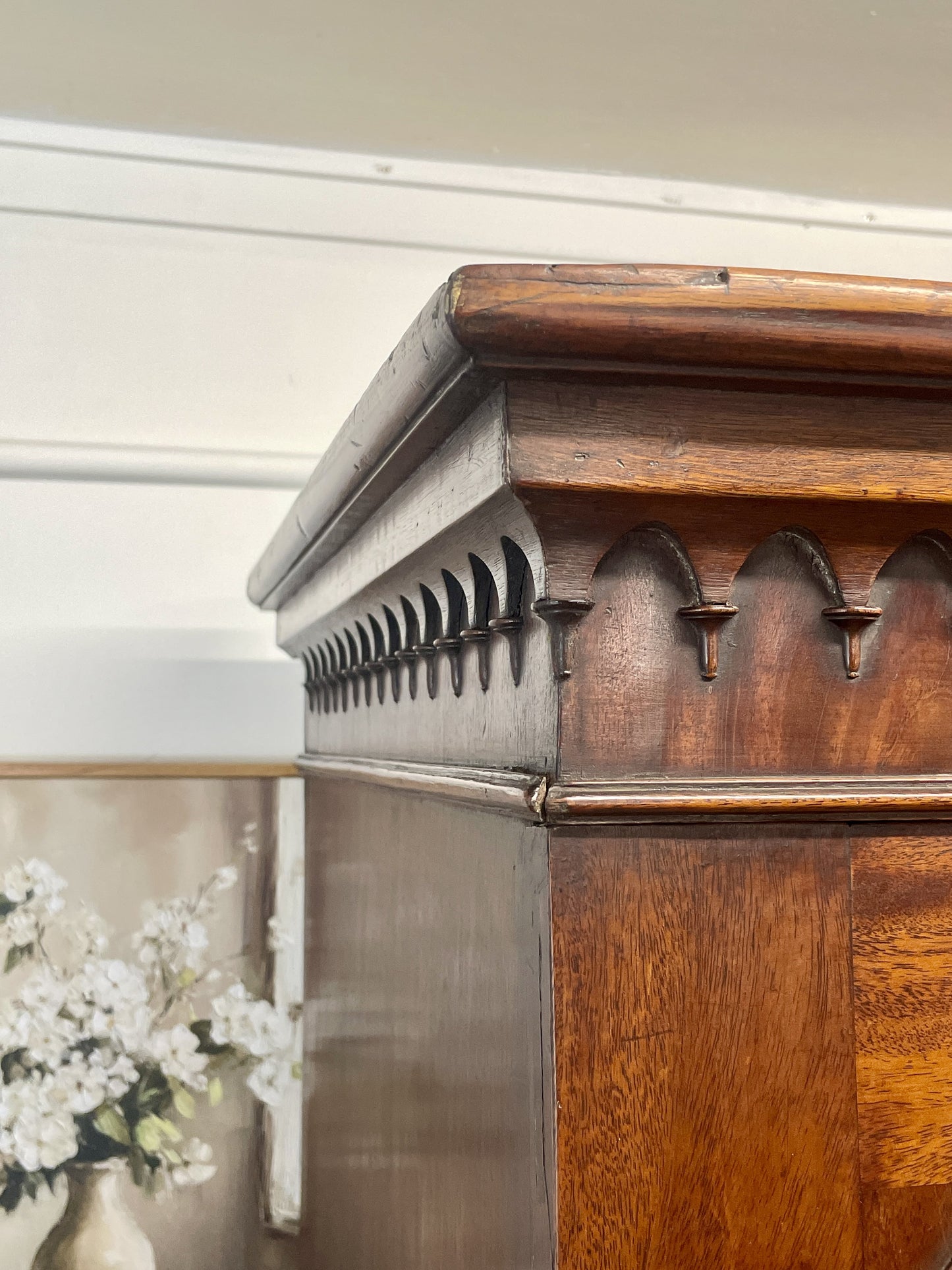 Wooden cabinet with decorative metal accents and a blurred floral background