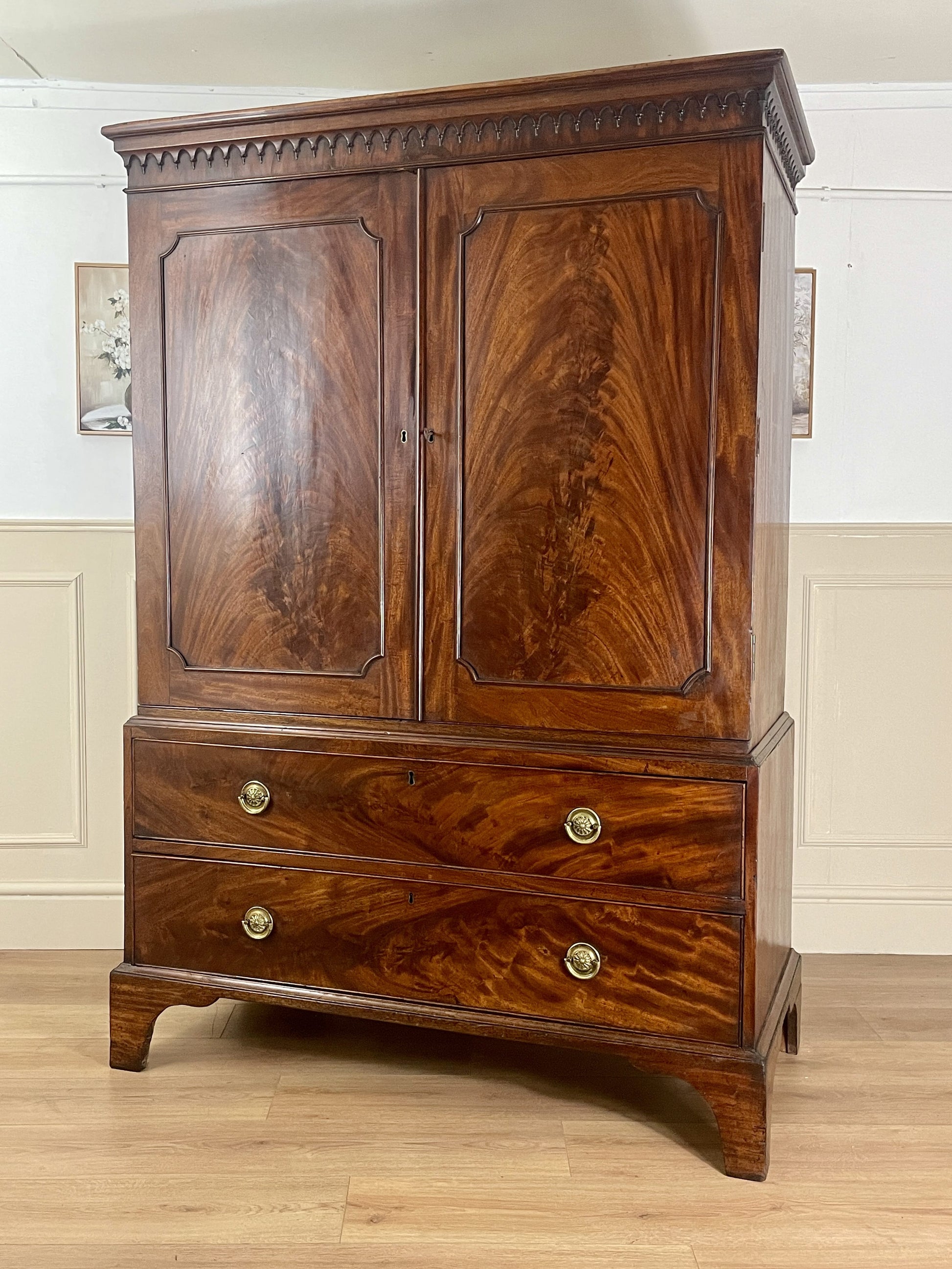 Wooden armoire with two doors and two drawers on a wooden floor.