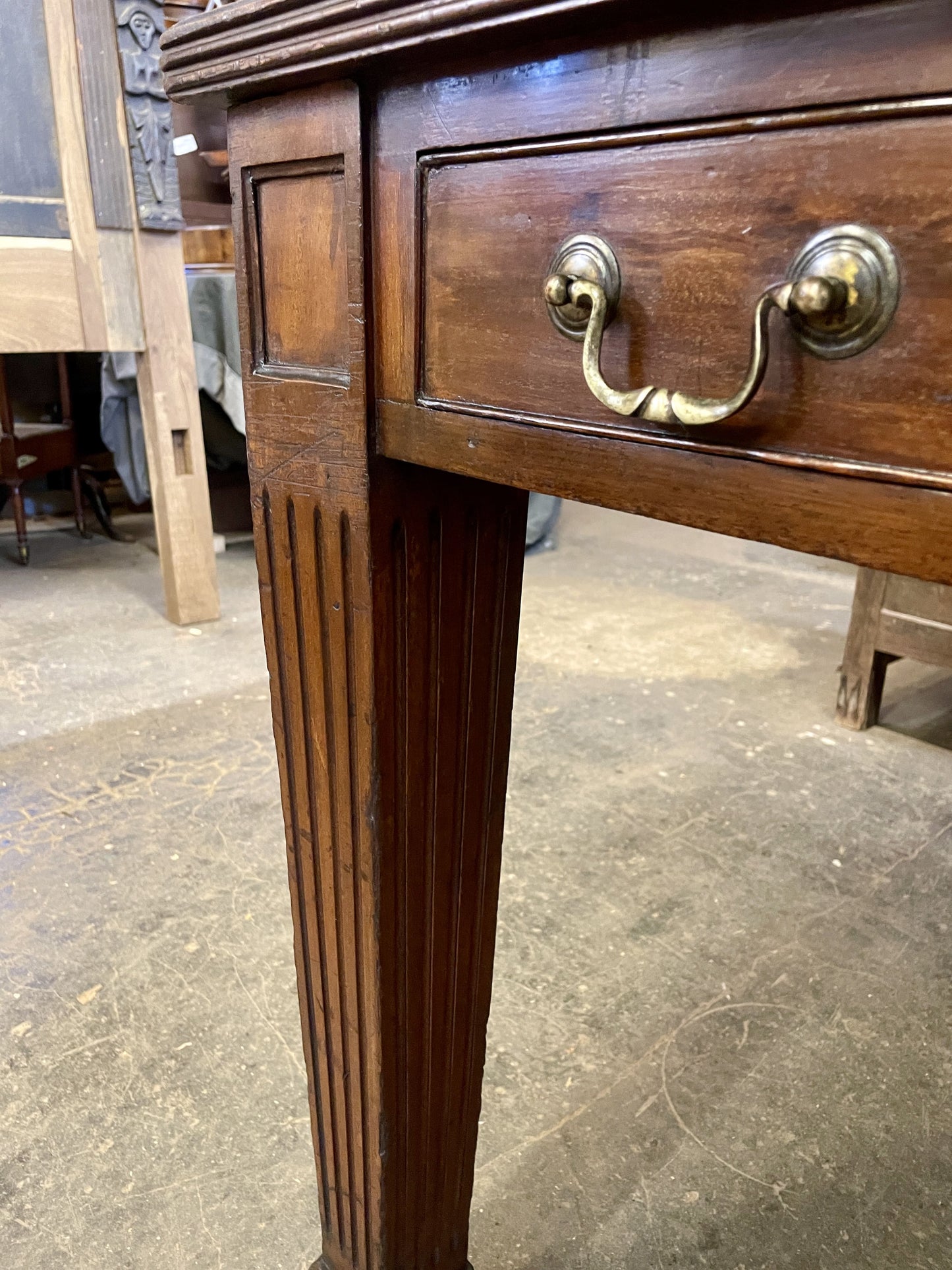 Wooden desk with a brass handle on a concrete floor