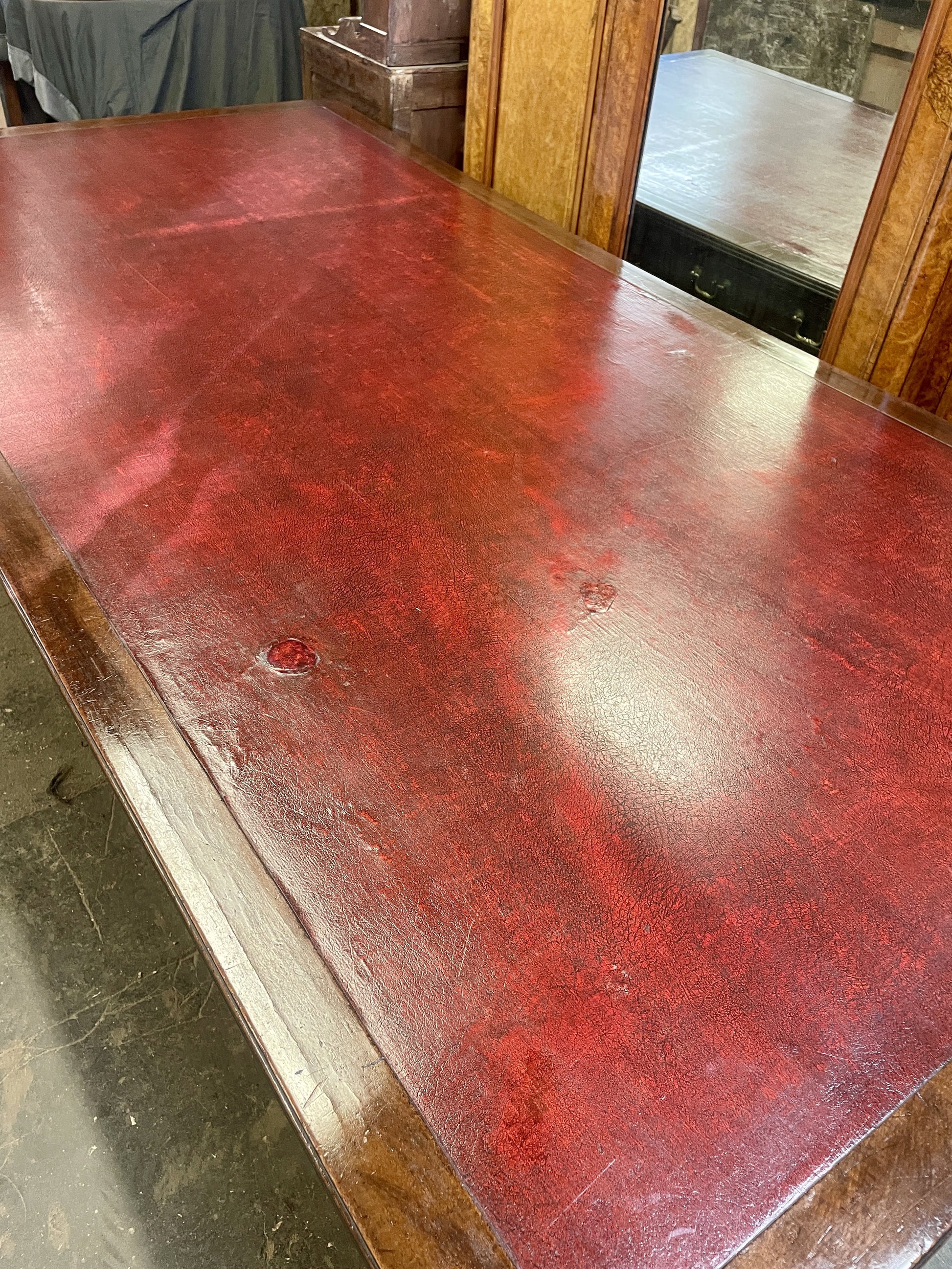 Red leather surface with visible wear and tear on a wooden table.