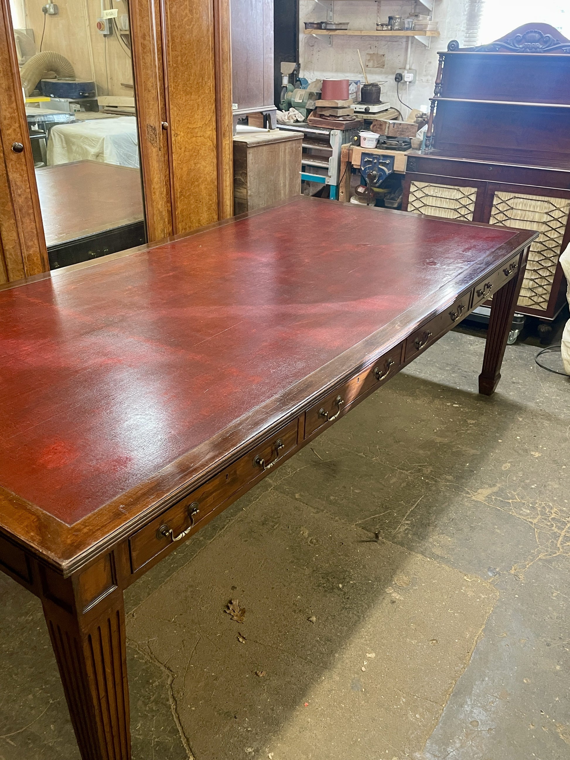 Large wooden table in a room with a kitchen in the background