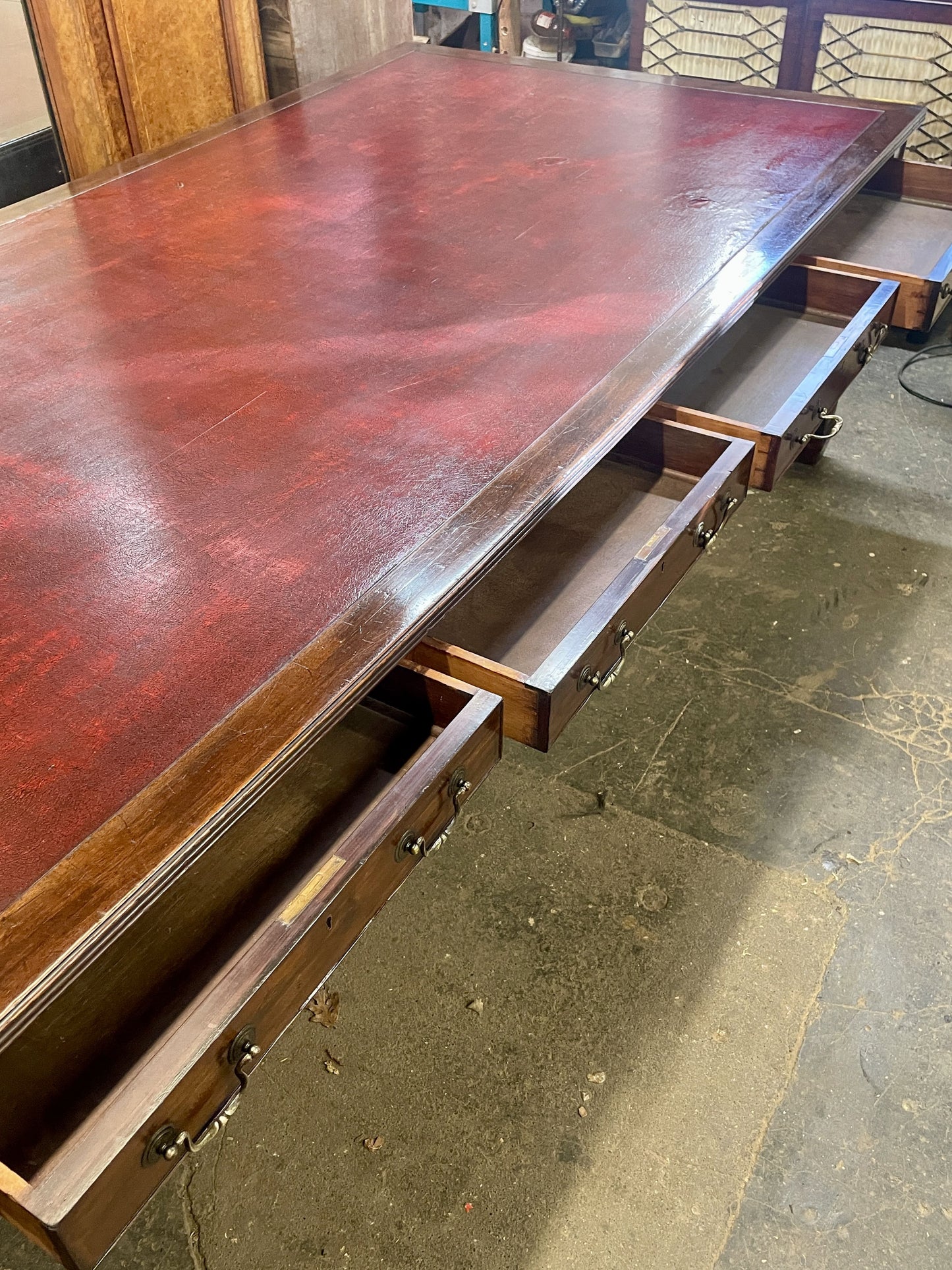 Large wooden desk with drawers on a concrete floor