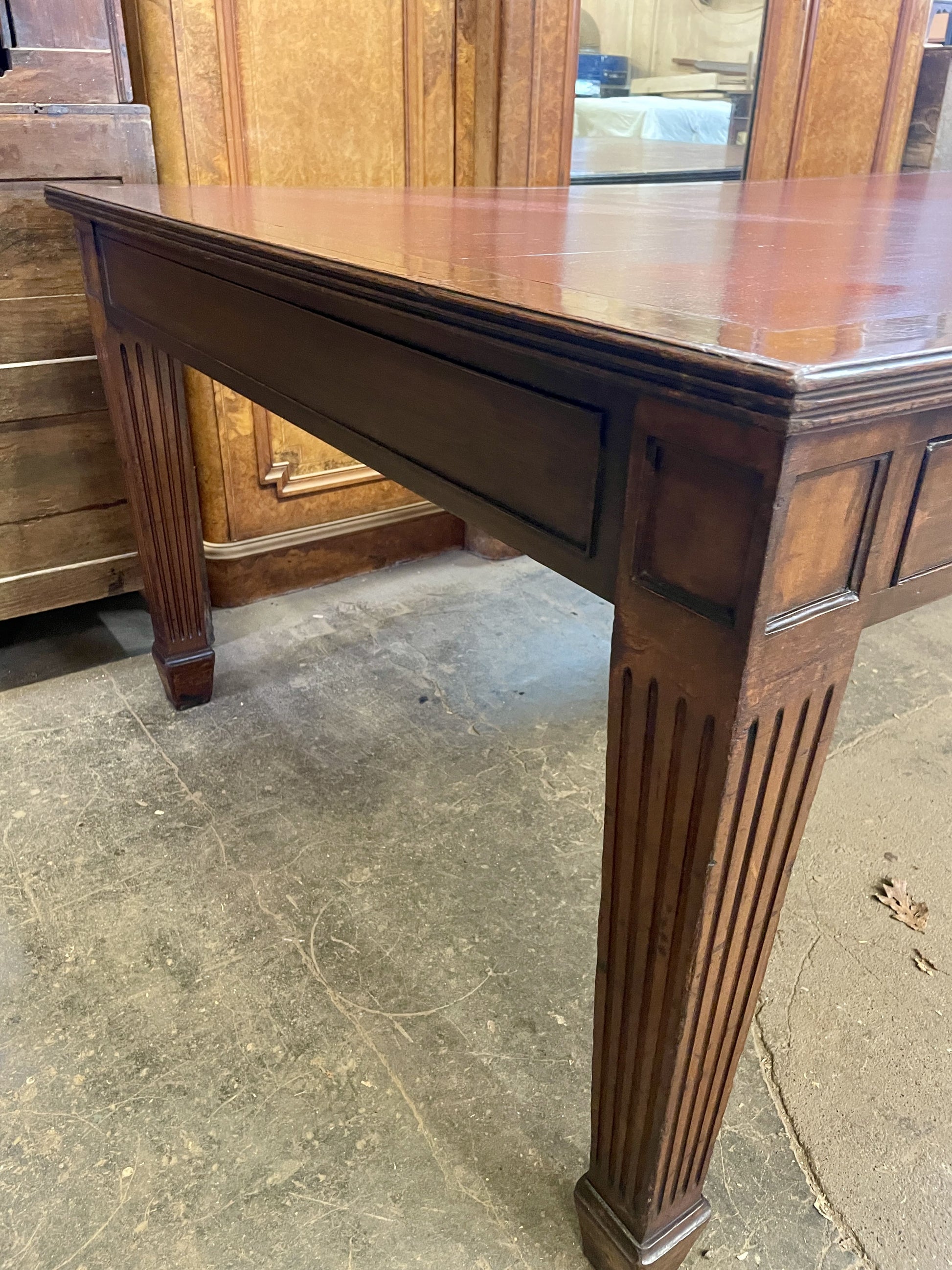Wooden table with a rustic finish on a concrete floor.