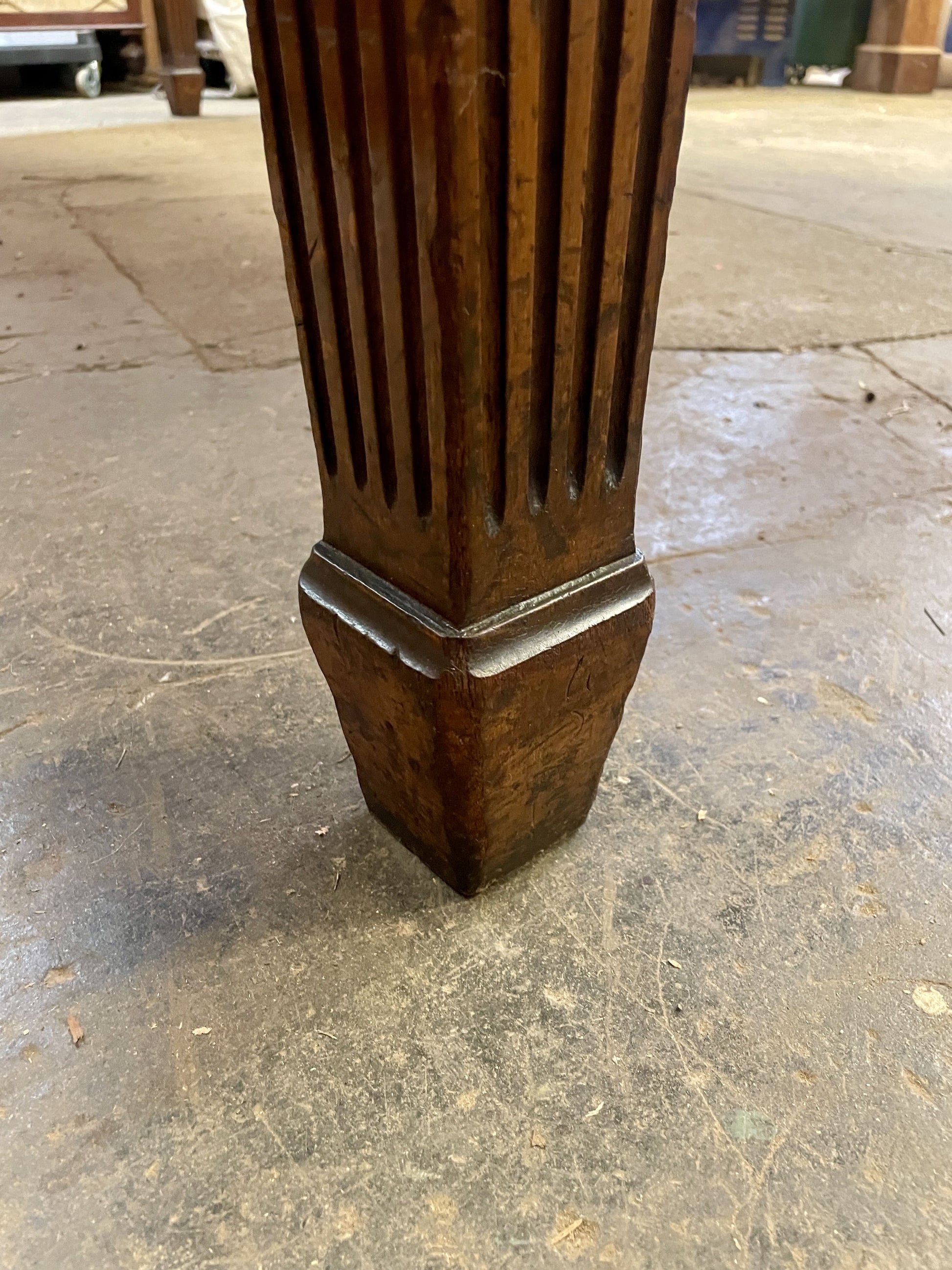 Wooden pedestal leg on a concrete floor