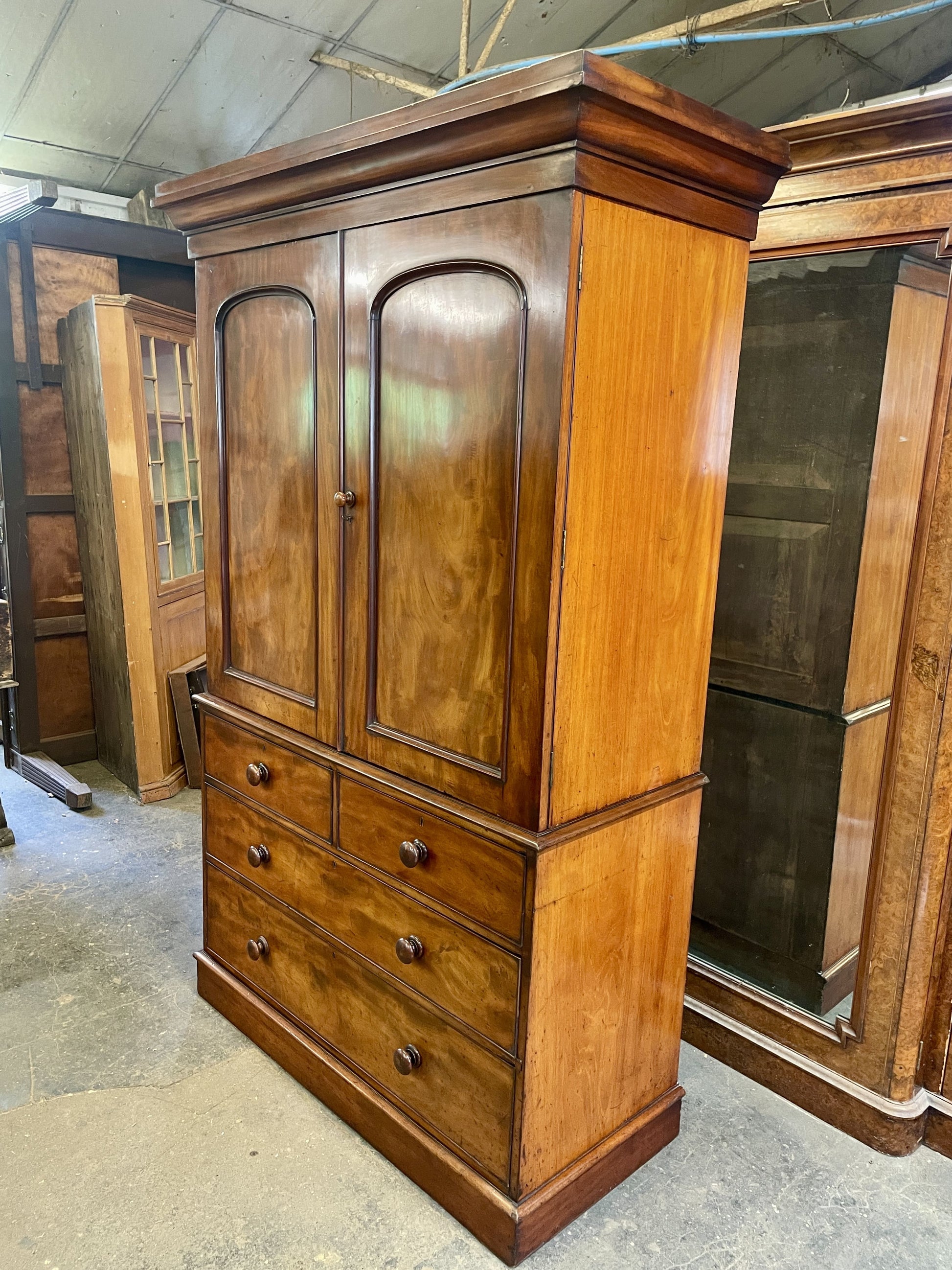 Wooden wardrobe with two doors and four drawers in a storage room.