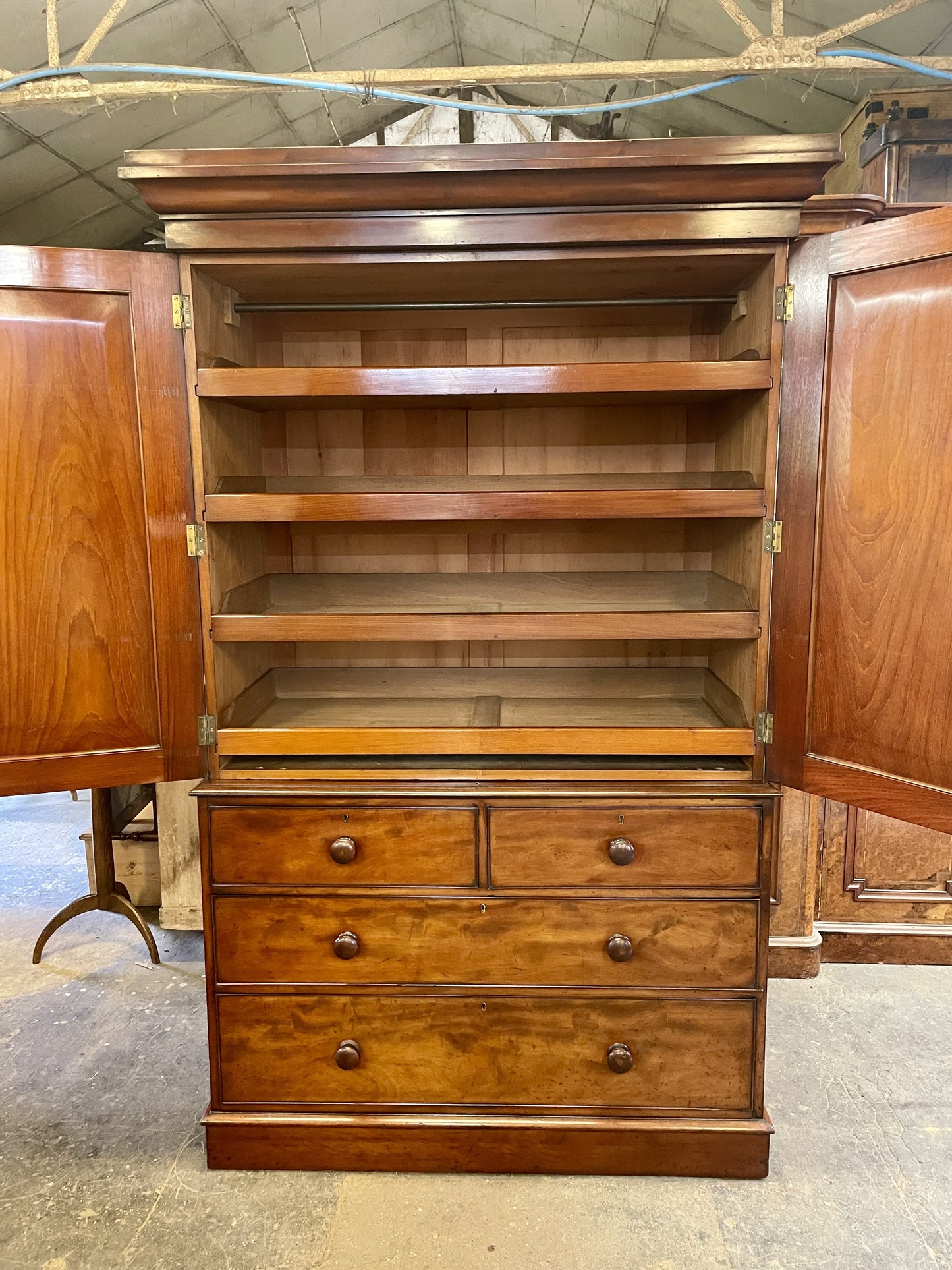 Wooden cabinet with open doors and drawers in a warehouse setting