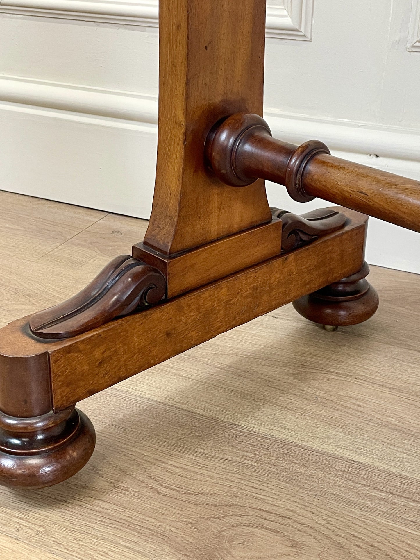Wooden chair leg with decorative bracket on a wooden floor.