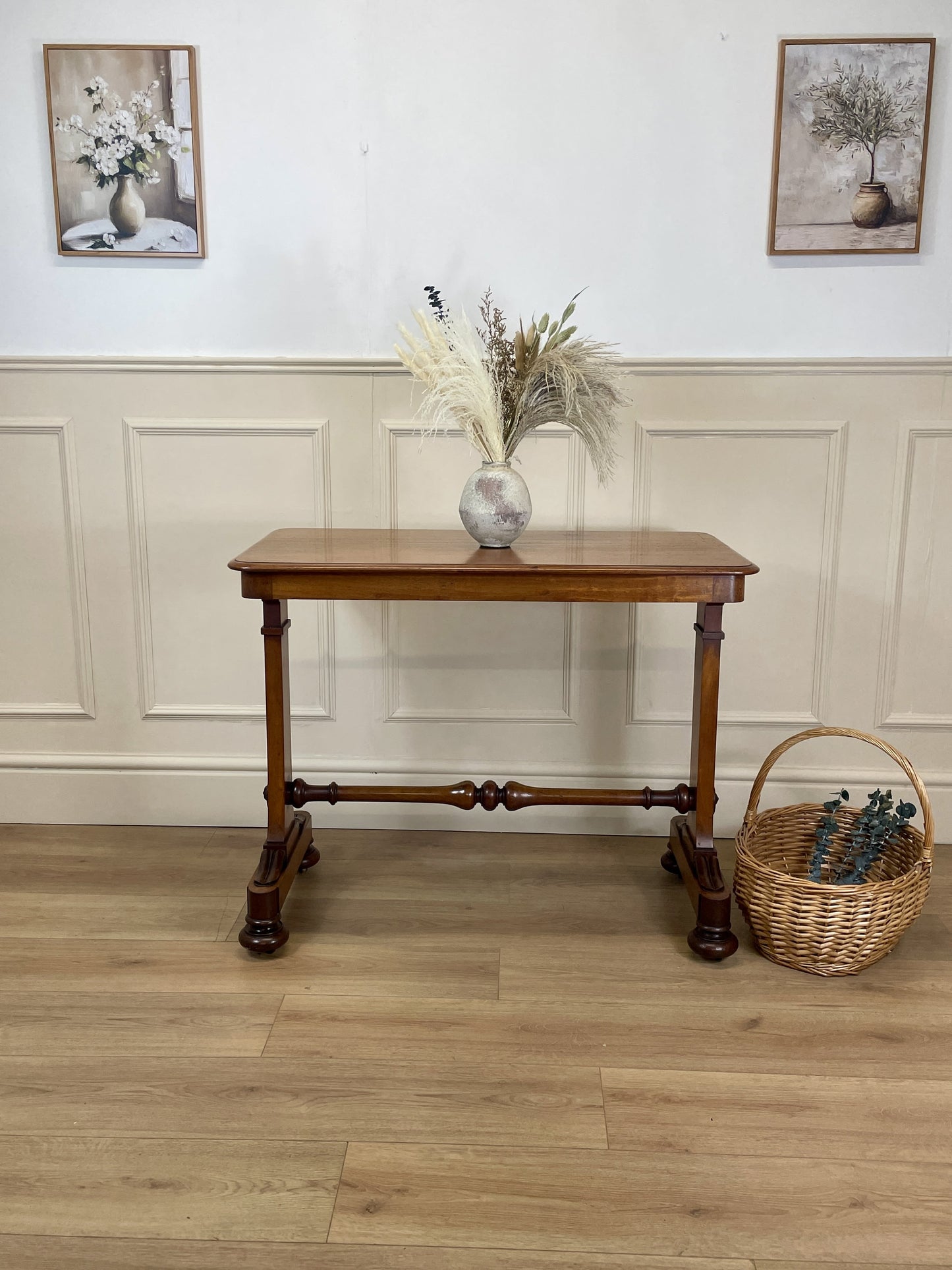 Wooden table with decorative items against a wall with framed pictures.