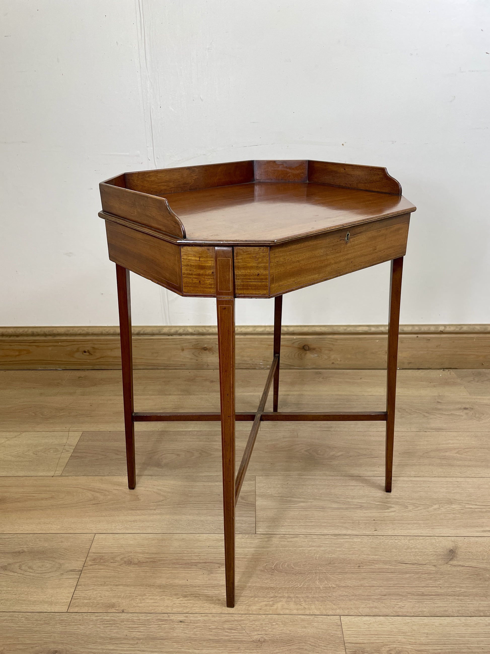 Wooden hexagonal side table on a wooden floor with a white wall background