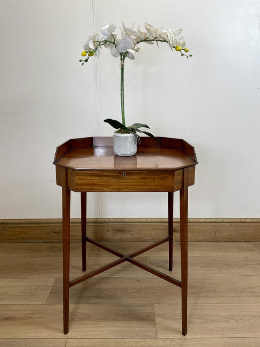 Wooden side table with a white orchid in a pot on a plain background