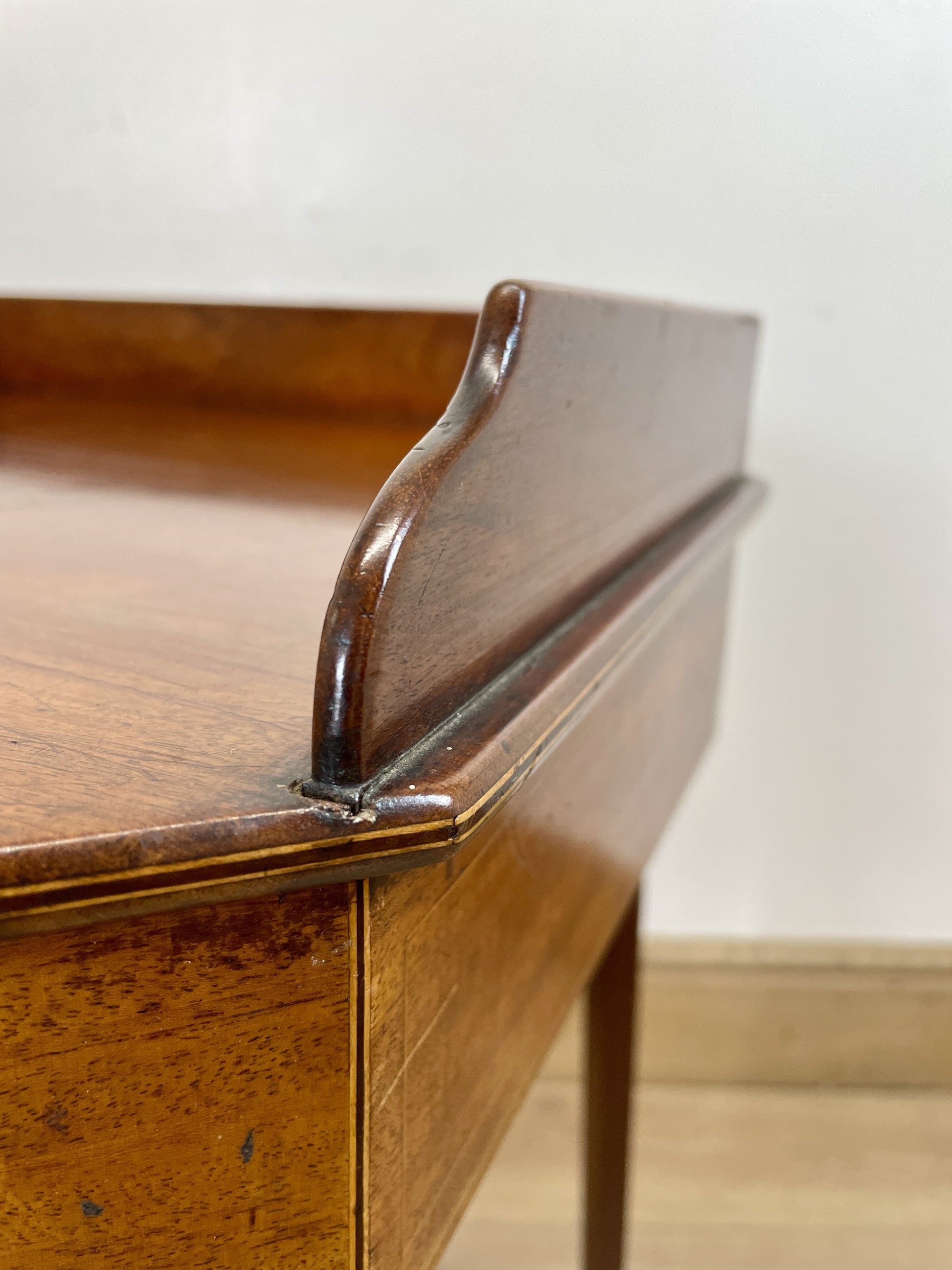 Close-up of a wooden desk corner with a white wall background