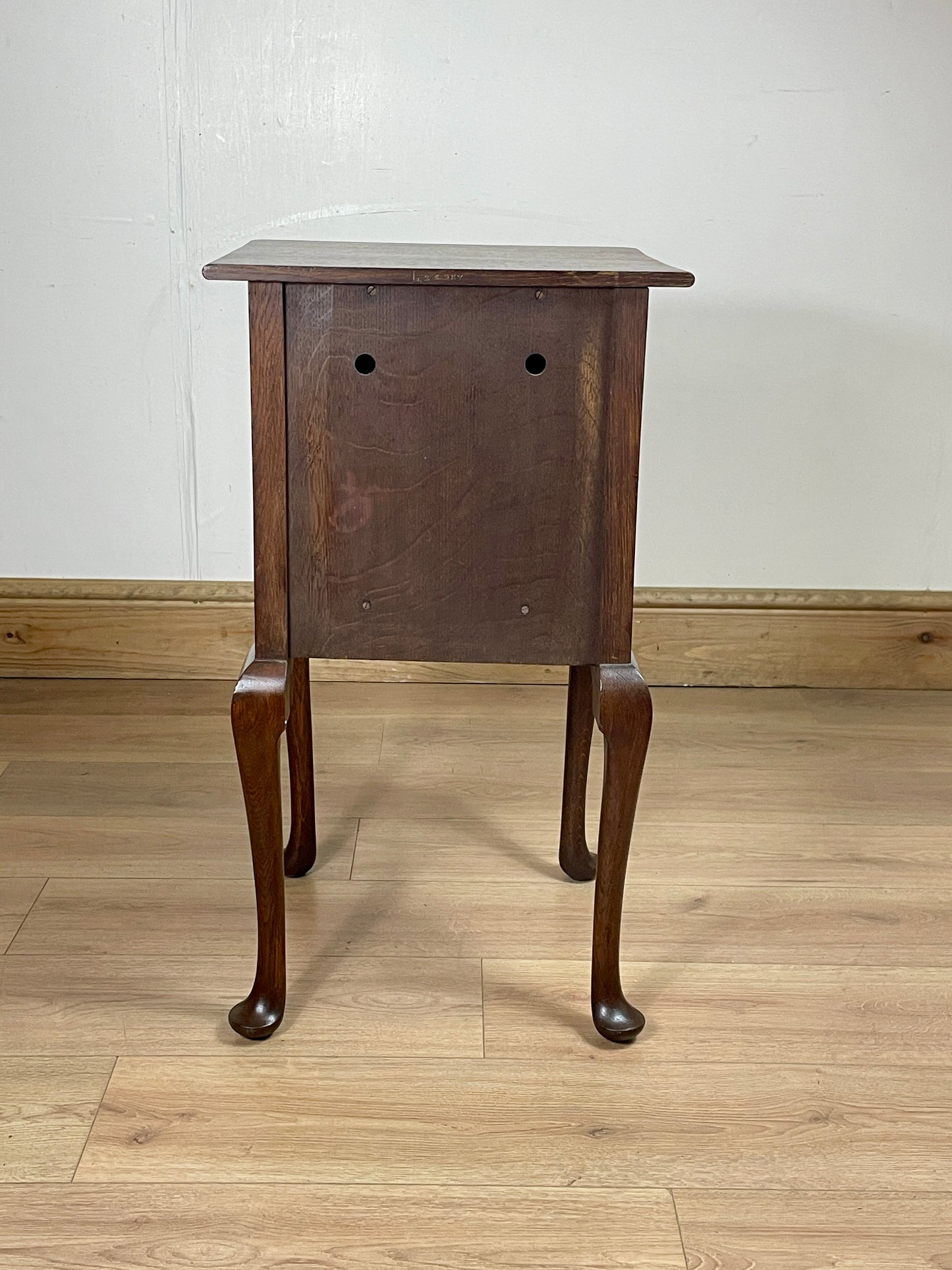 Wooden side table on a wooden floor against a white wall