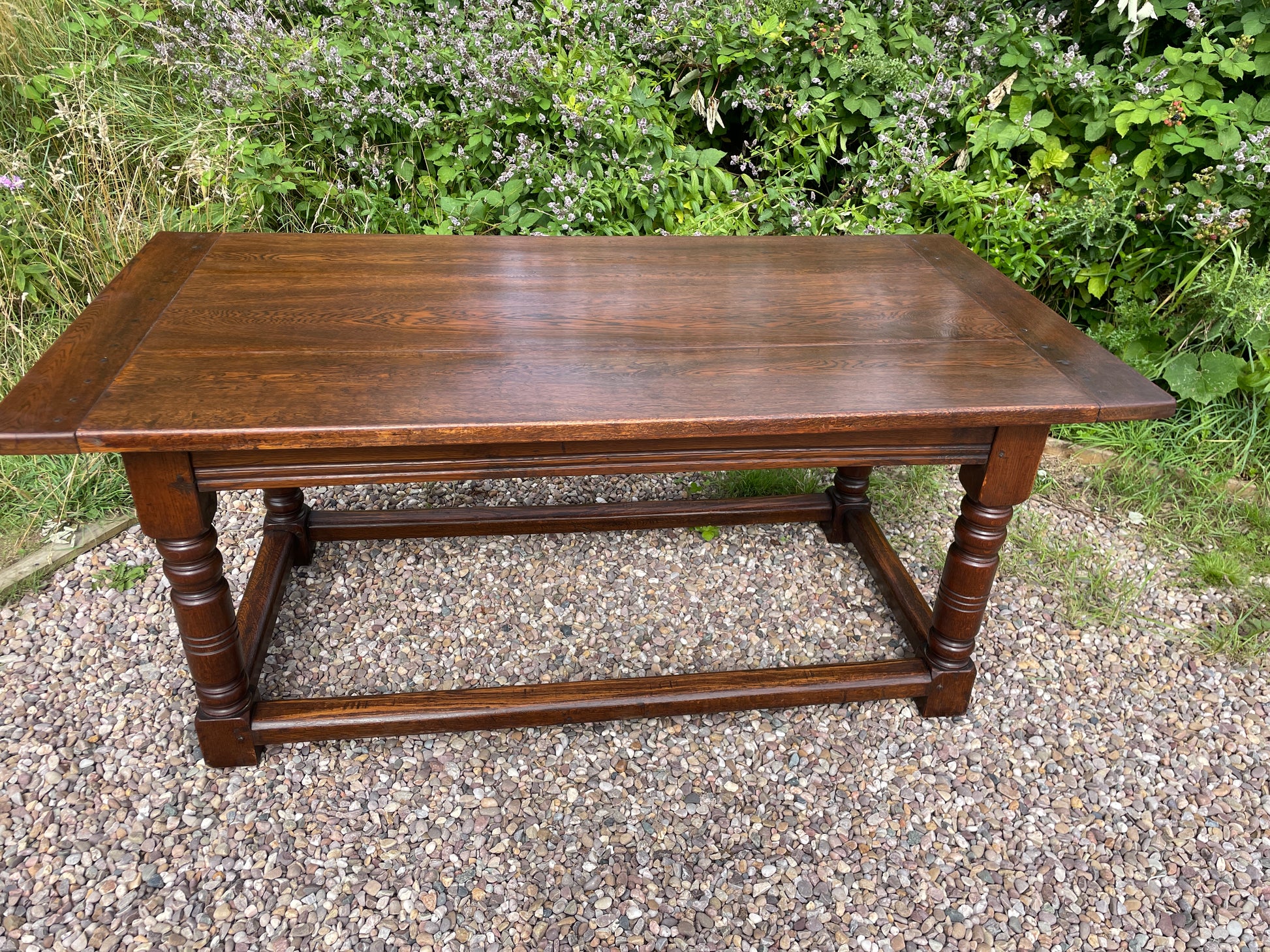 Wooden table outdoors on a gravel surface with greenery in the background