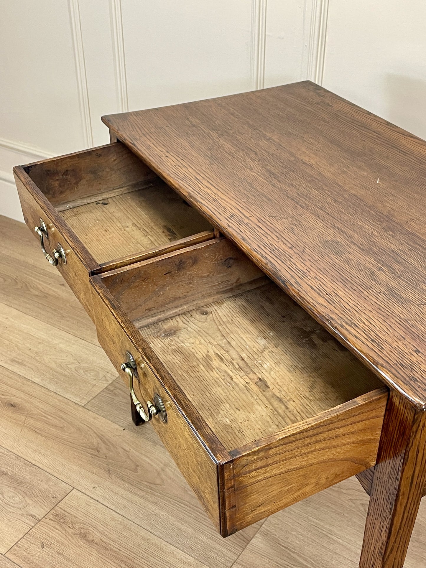 Wooden desk with an open drawer on a wooden floor.