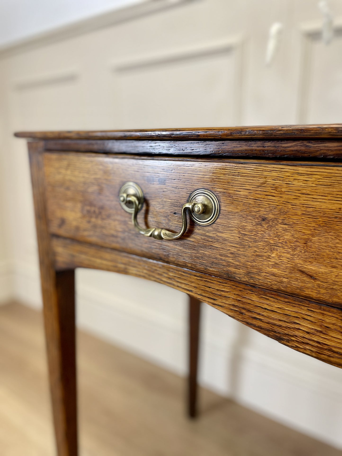 Wooden drawer with brass handle on a light-colored wall background